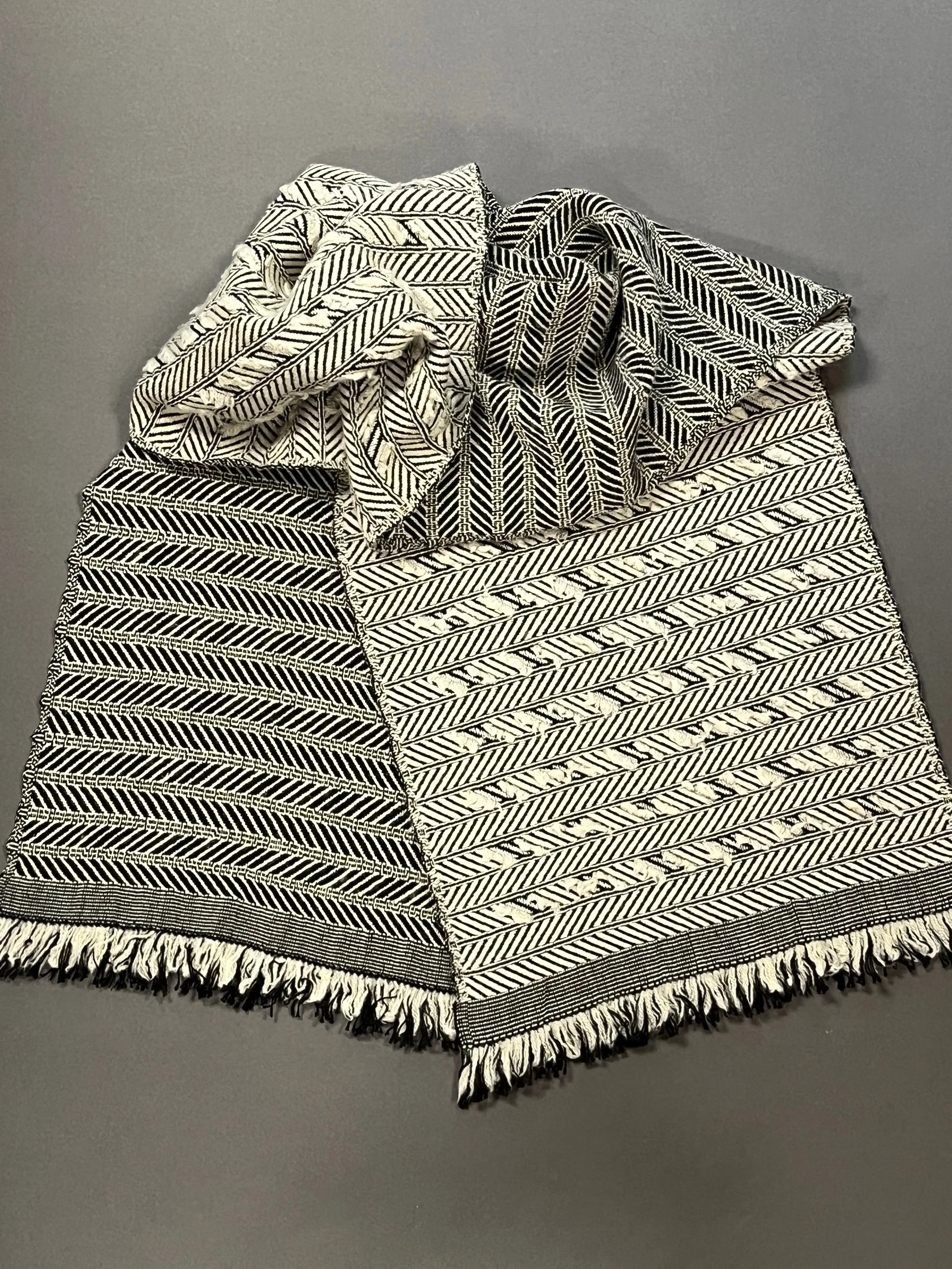 Woven in 50% silk/50% wool blend, the scarf exhibits two distinct opposite sides; the floats on one side have been snipped to create a fuzzy texture