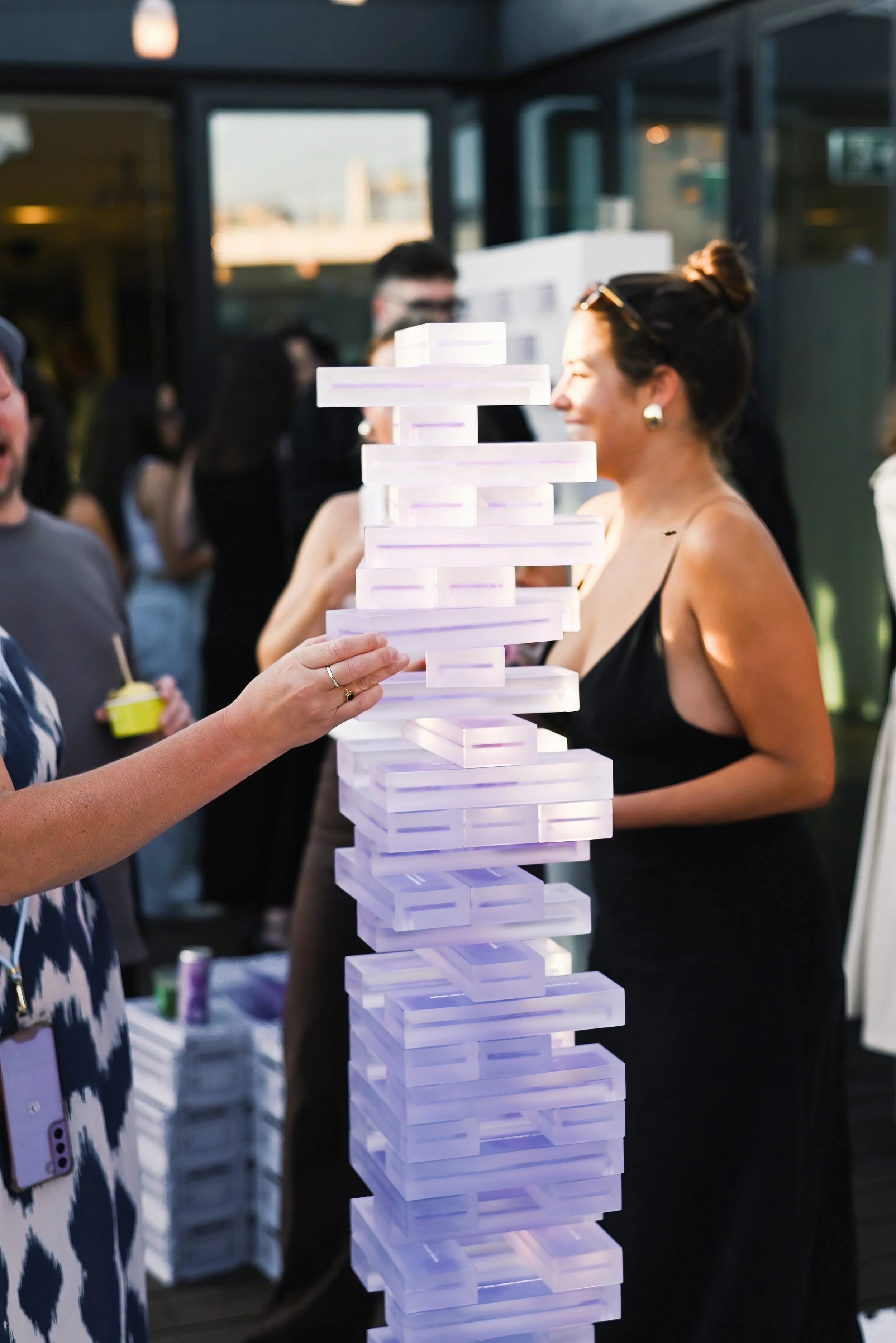 People playing a giant Jenga game at an outdoor gathering or party.