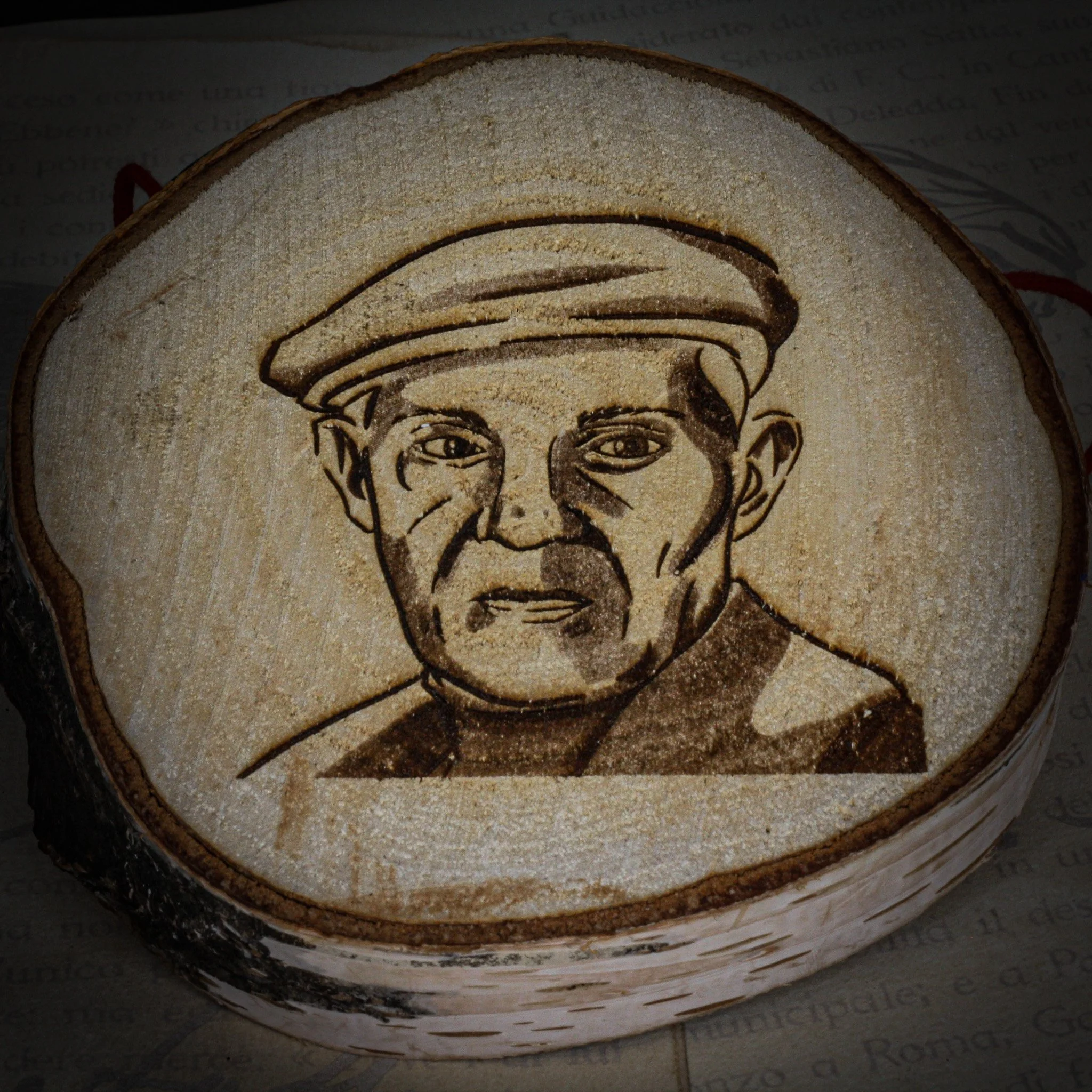 Ritratto disegnato di un uomo anziano con berretto, inciso su un pezzo di legno.