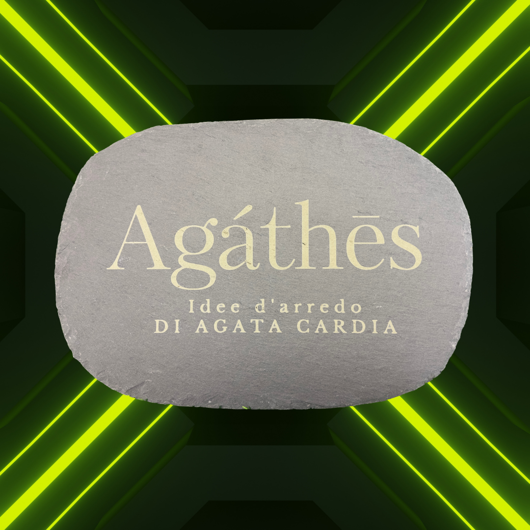 Un cartello di pietra con scritto 'Agathés, Idee d'arredo di Agata Cardia' su sfondo nero con linee di luce verde neon
