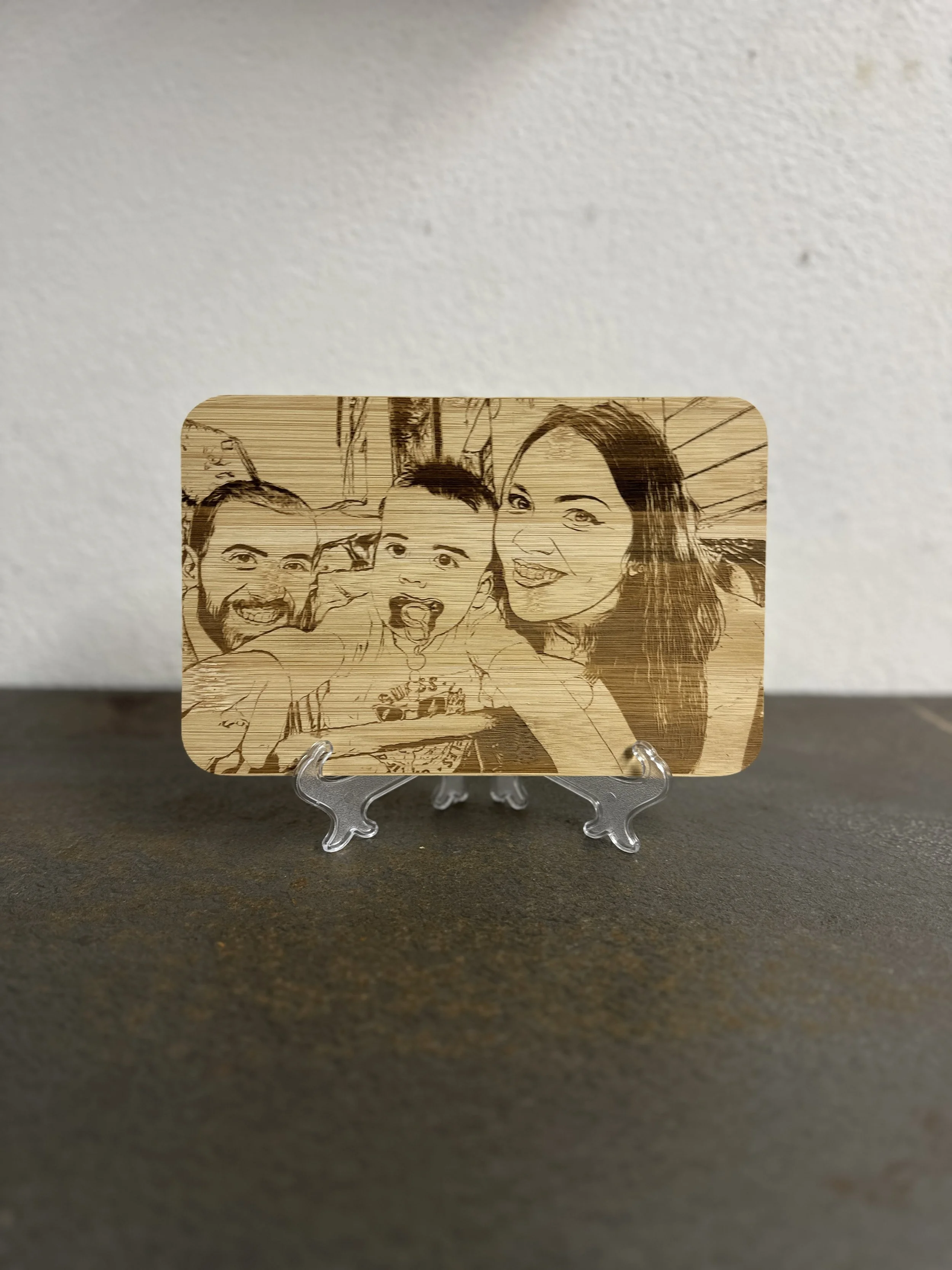 Una lastra di legno intagliata con una scena di una famiglia sorridente, posizionata su un supporto trasparente.