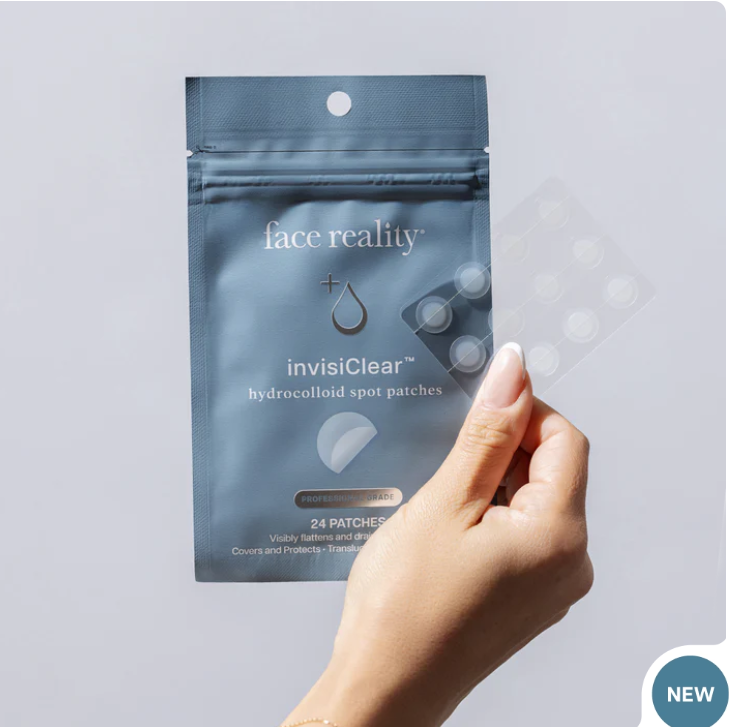 A hand holding a pack of Face Reality InvisiClear hydrocolloid spot patches against a light gray background.