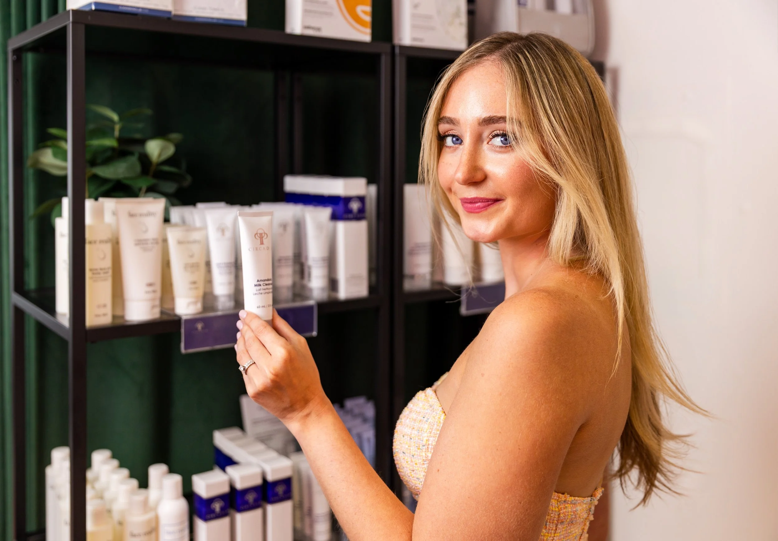 A woman with blonde hair looking at skincare products on a store shelf.