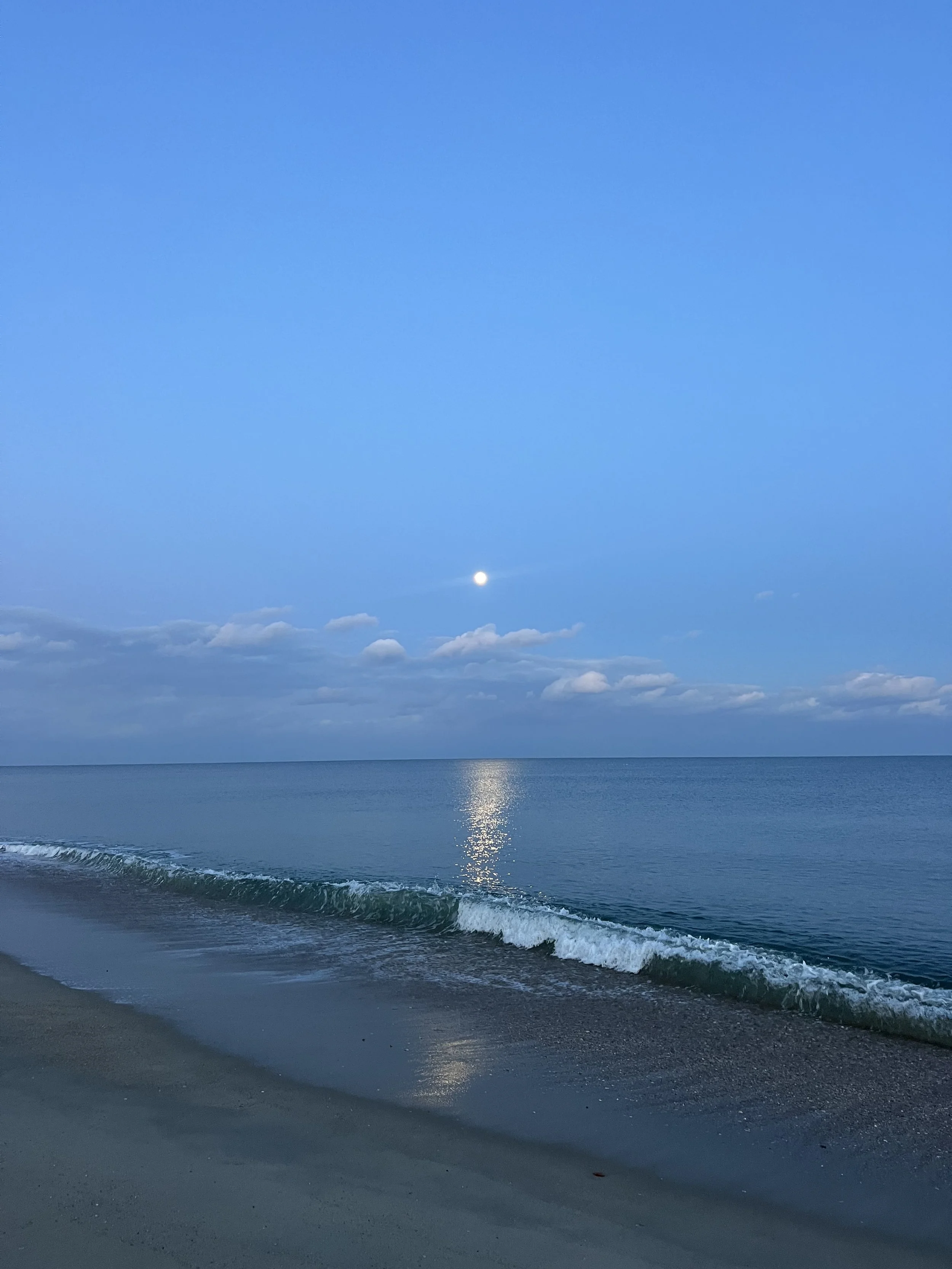 Long Branch New Jersey Beach with calm water and moon behind reflecting off the ocean