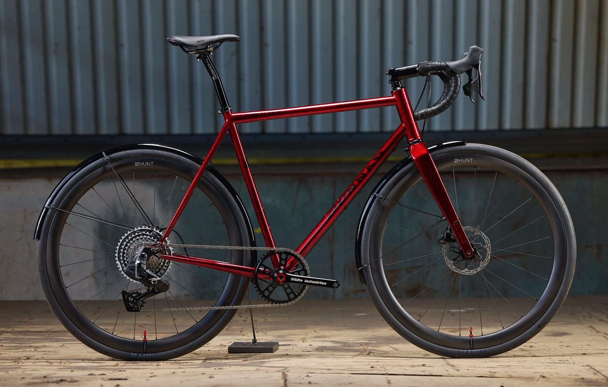 Red mountain bike with black wheels and tires, set against a wooden floor and metal background.