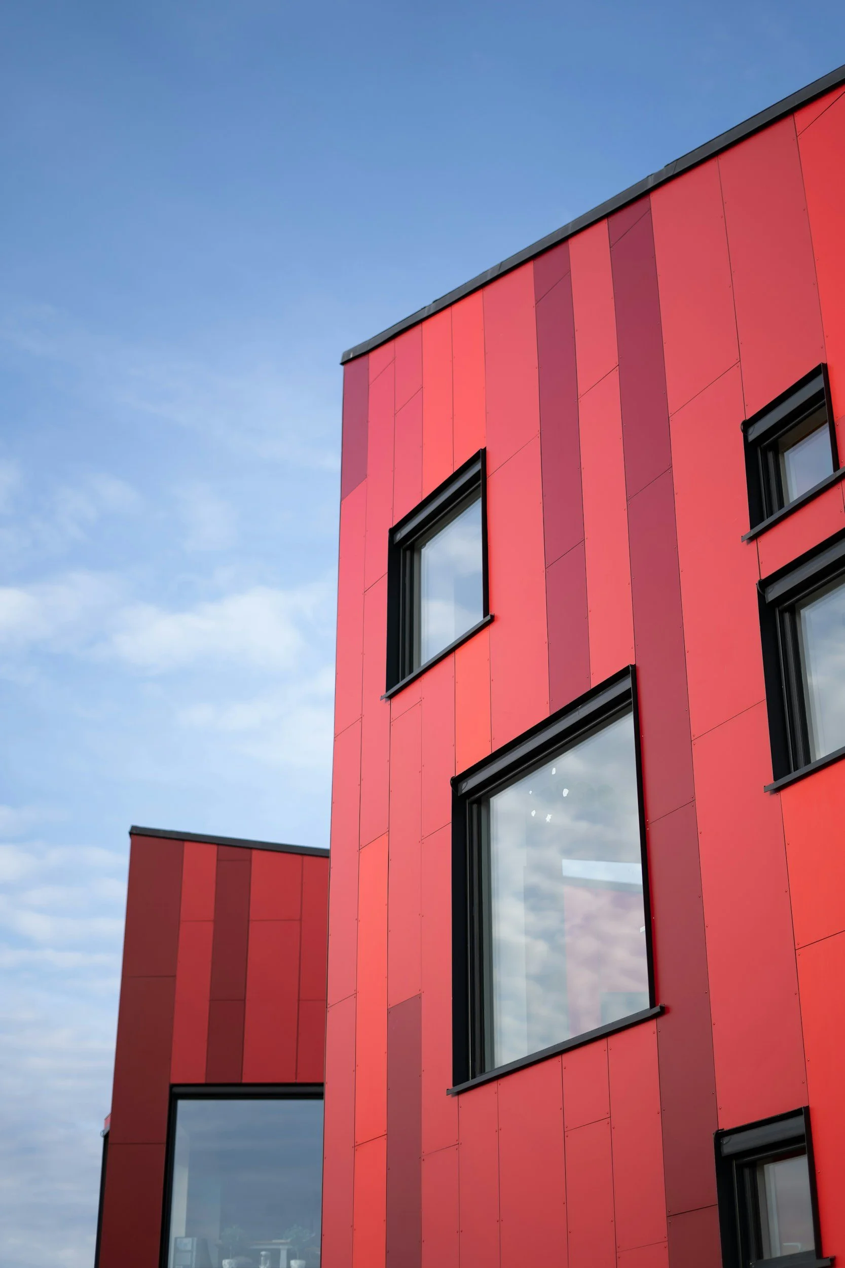 Side angle of two red residential buildings with multiple high performance windows