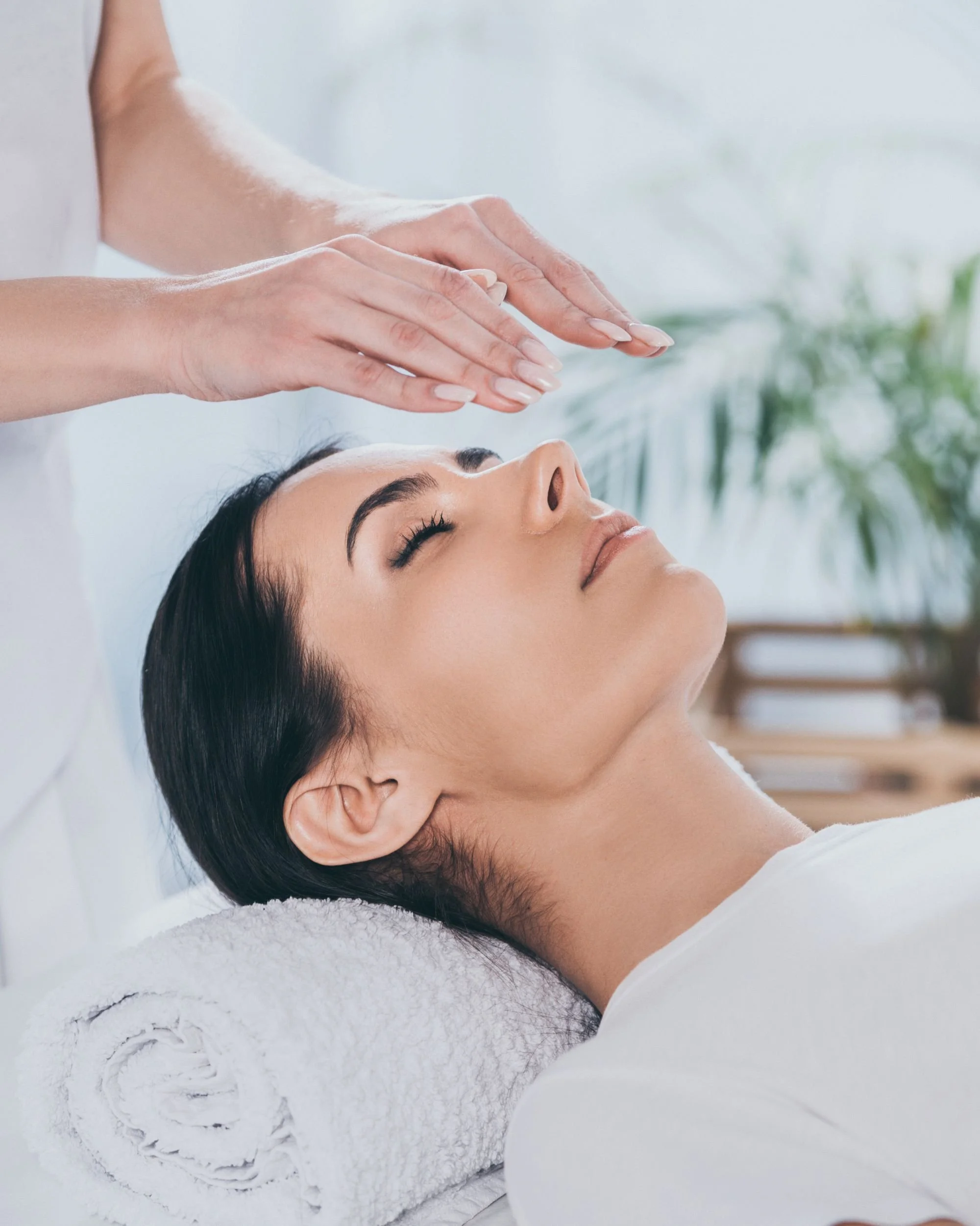 Woman receiving a facial treatment at a spa, lying on a white towel with closed eyes.