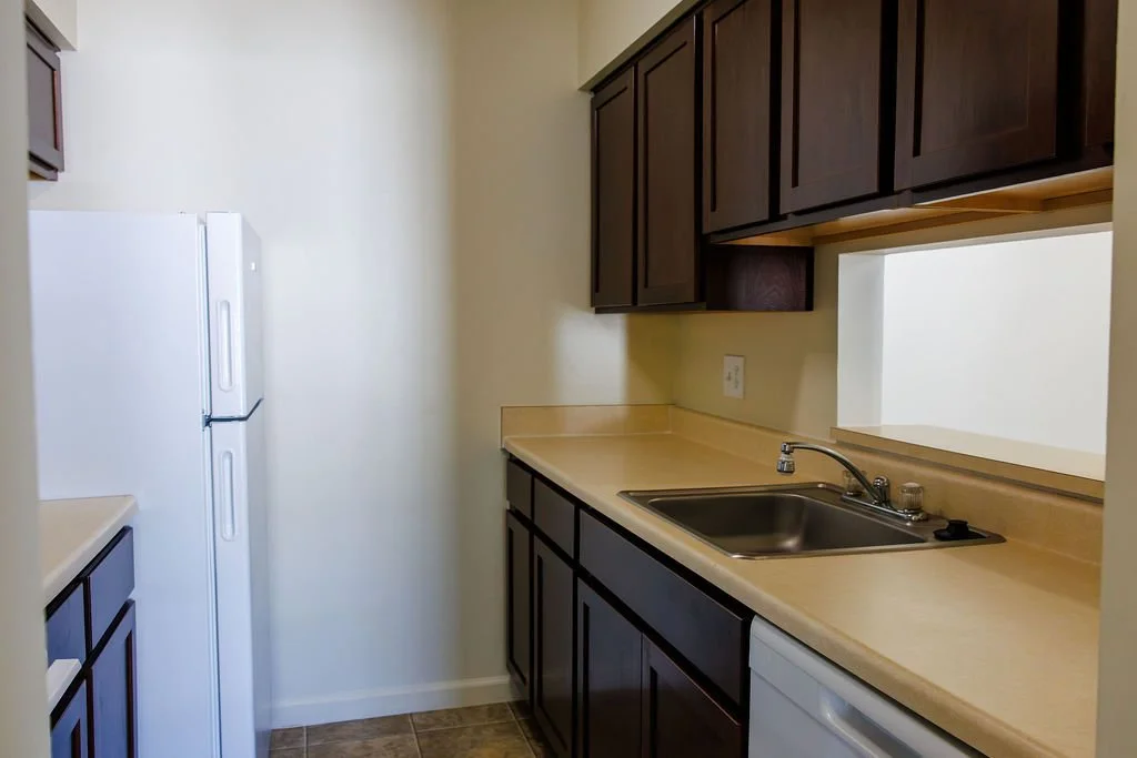 Kitchen with beige countertops, dark wood cabinets, a sink, and a white refrigerator.