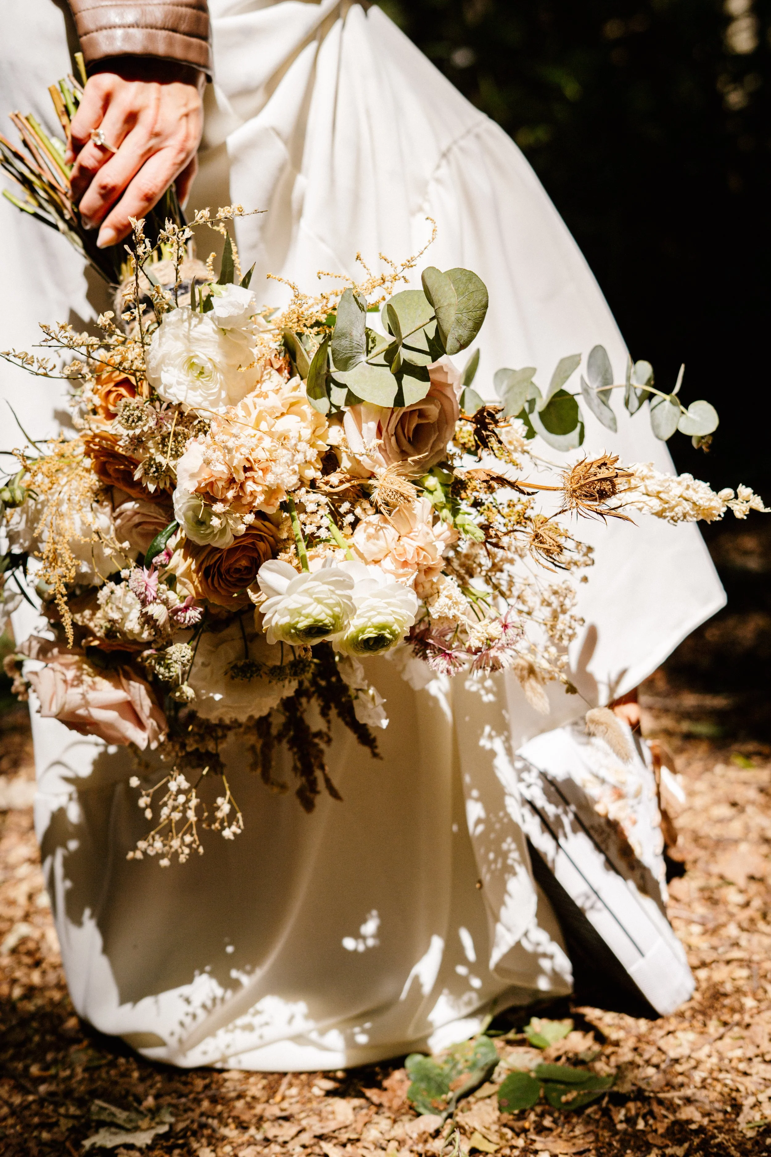 bride close up shot holding a bouquet of flowers down by her legs.