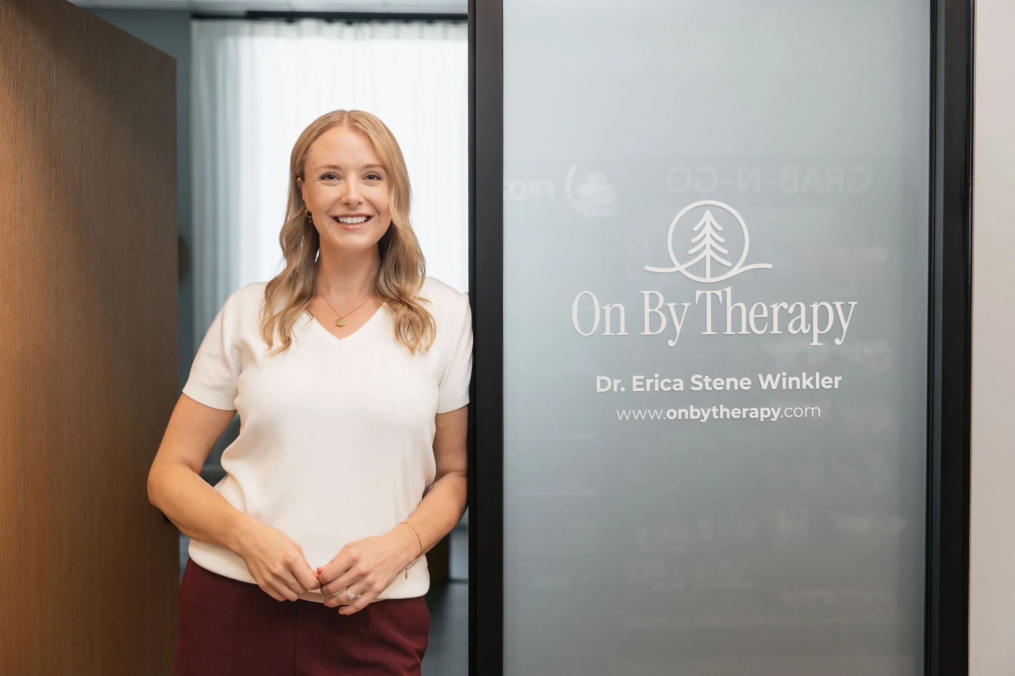 Dr. Erica Stene Winkler standing at the entrance to On By Therapy, her counseling practice in Fargo, ND