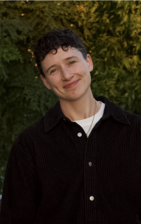 Carlo Sariego, wearing a black corduroy shirt, standing in front of lush foliage in New Haven, Connecticut.