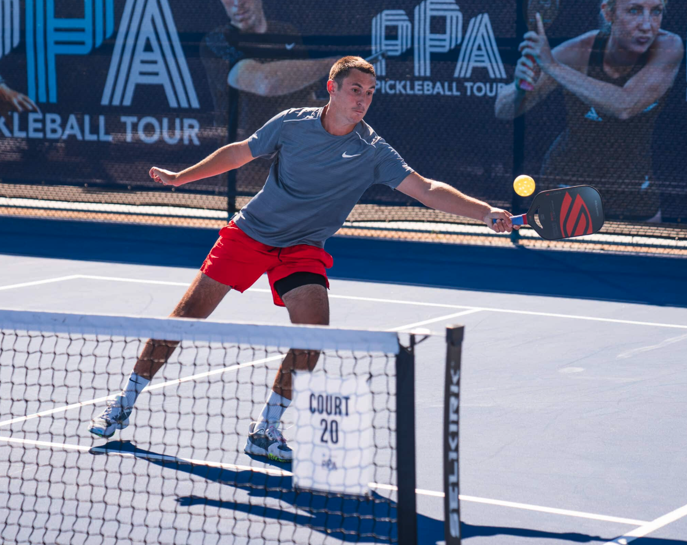 A man playing pickleball at an indoor court, holding a paddle and preparing to hit the ball.