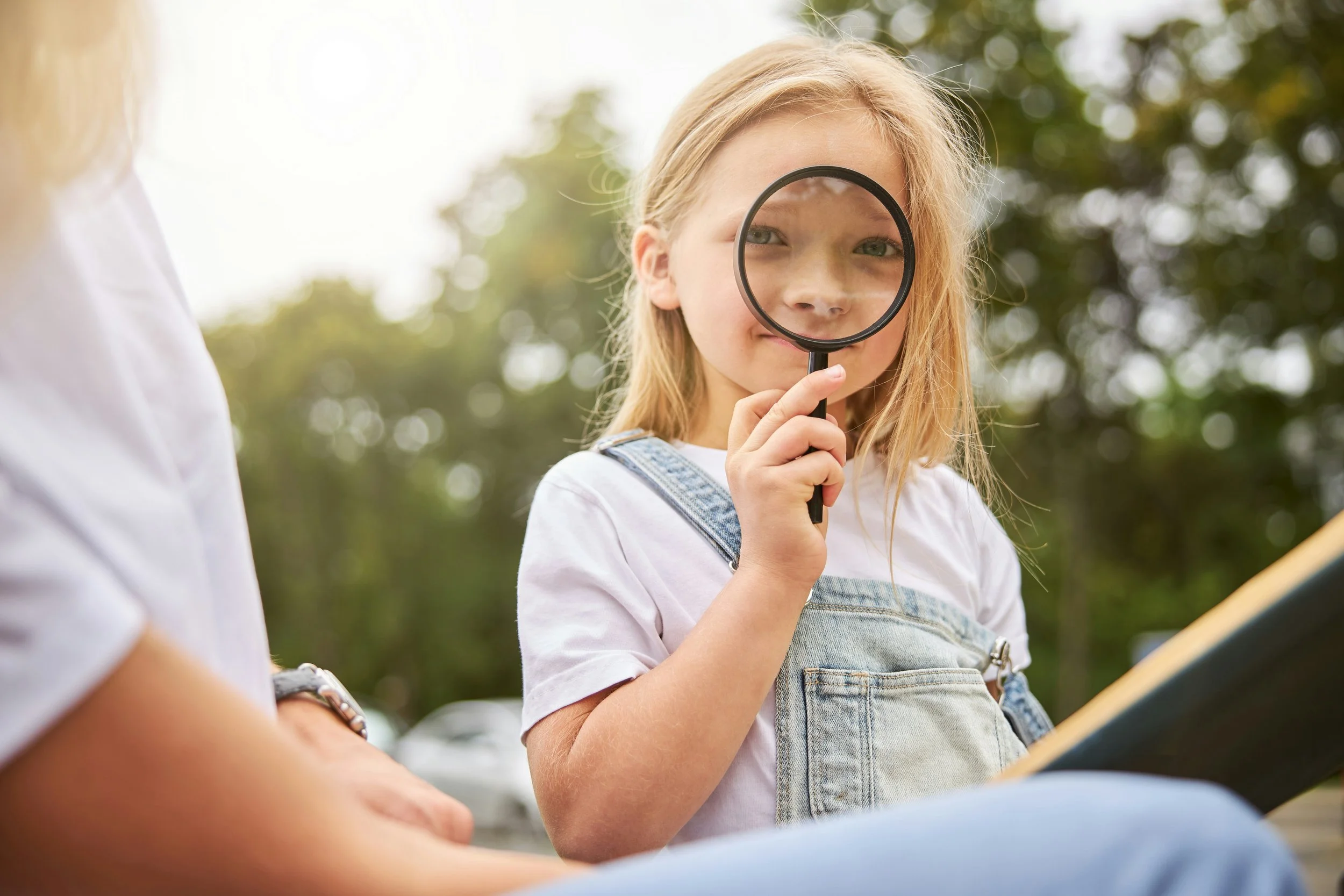 girl looking through a magnifying glass to camera