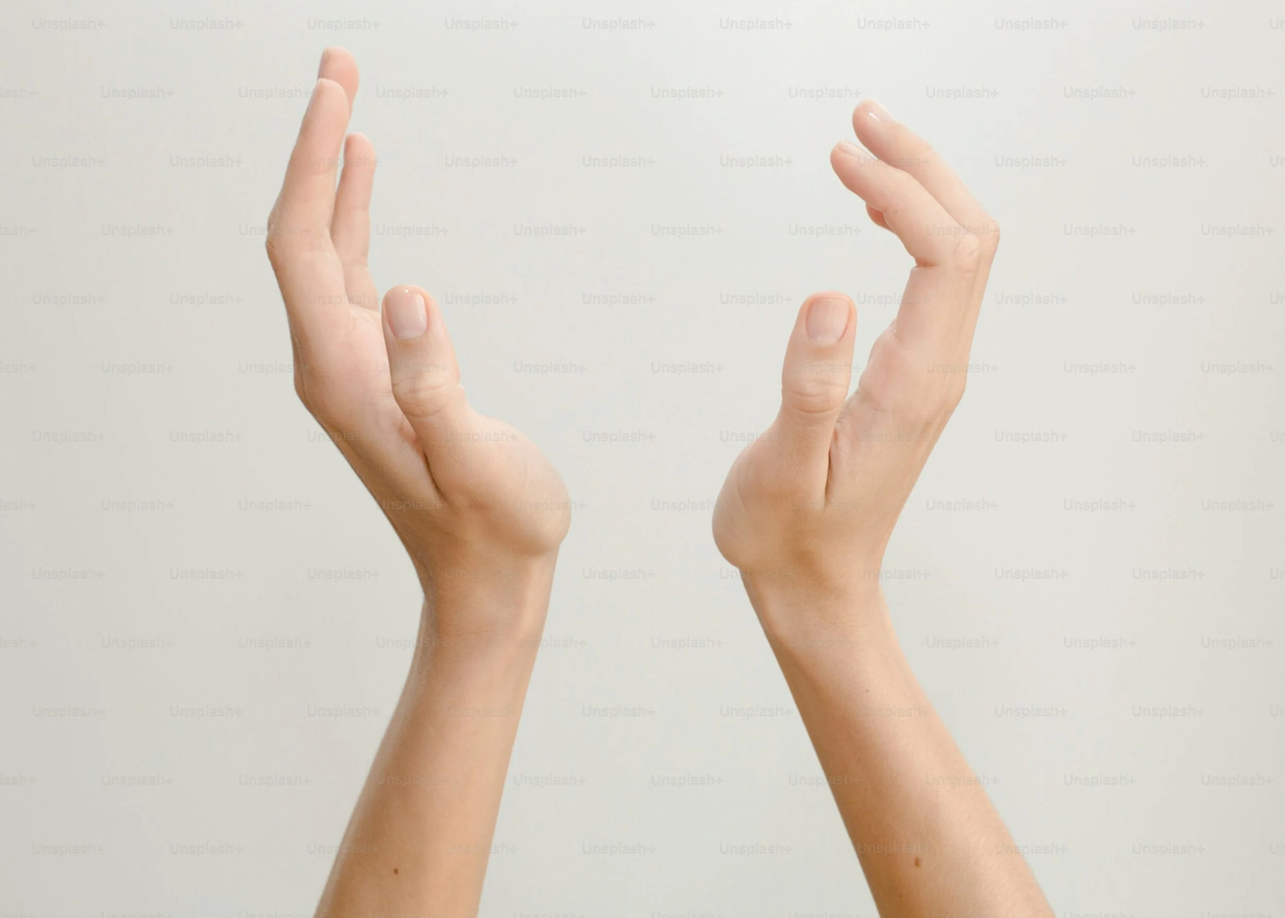 Two hands with palms facing each other, fingers slightly curved, positioned against a plain light background.