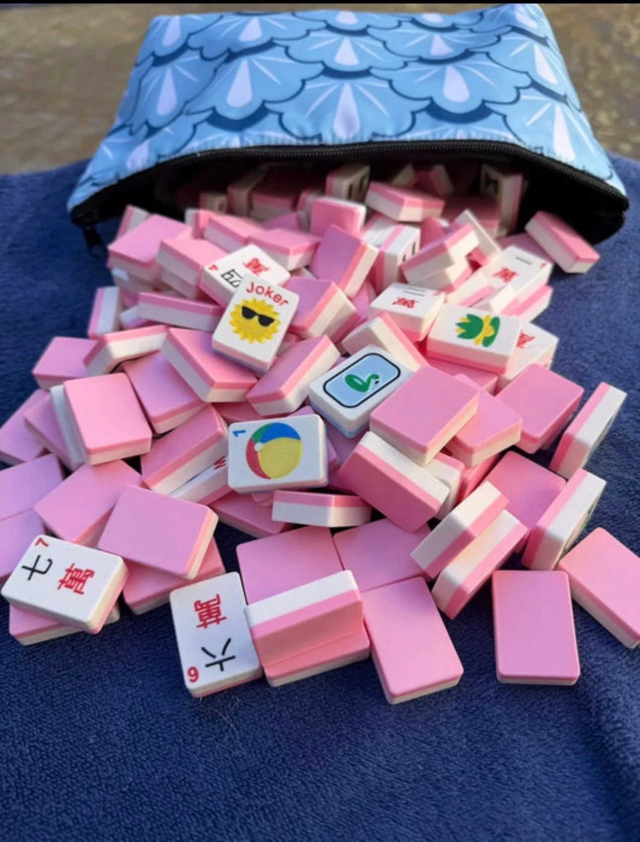 Close-up of Mahjong tiles with various Asian characters and symbols arranged on a green Mahjong game board.