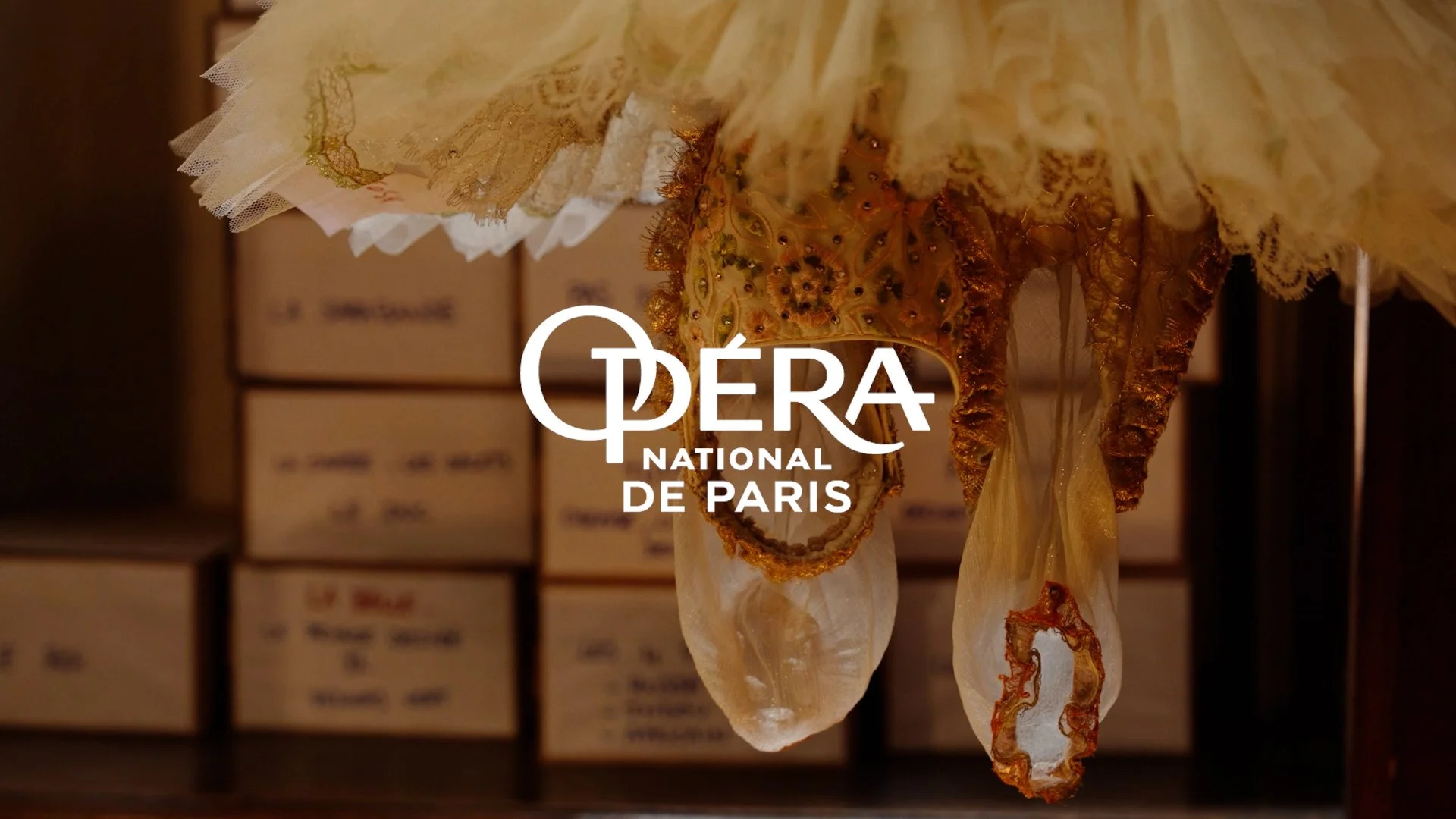 Suspension d'une décoration en tissu et fils, avec le texte 'OPÉRA NATIONAL DE PARIS' superposé