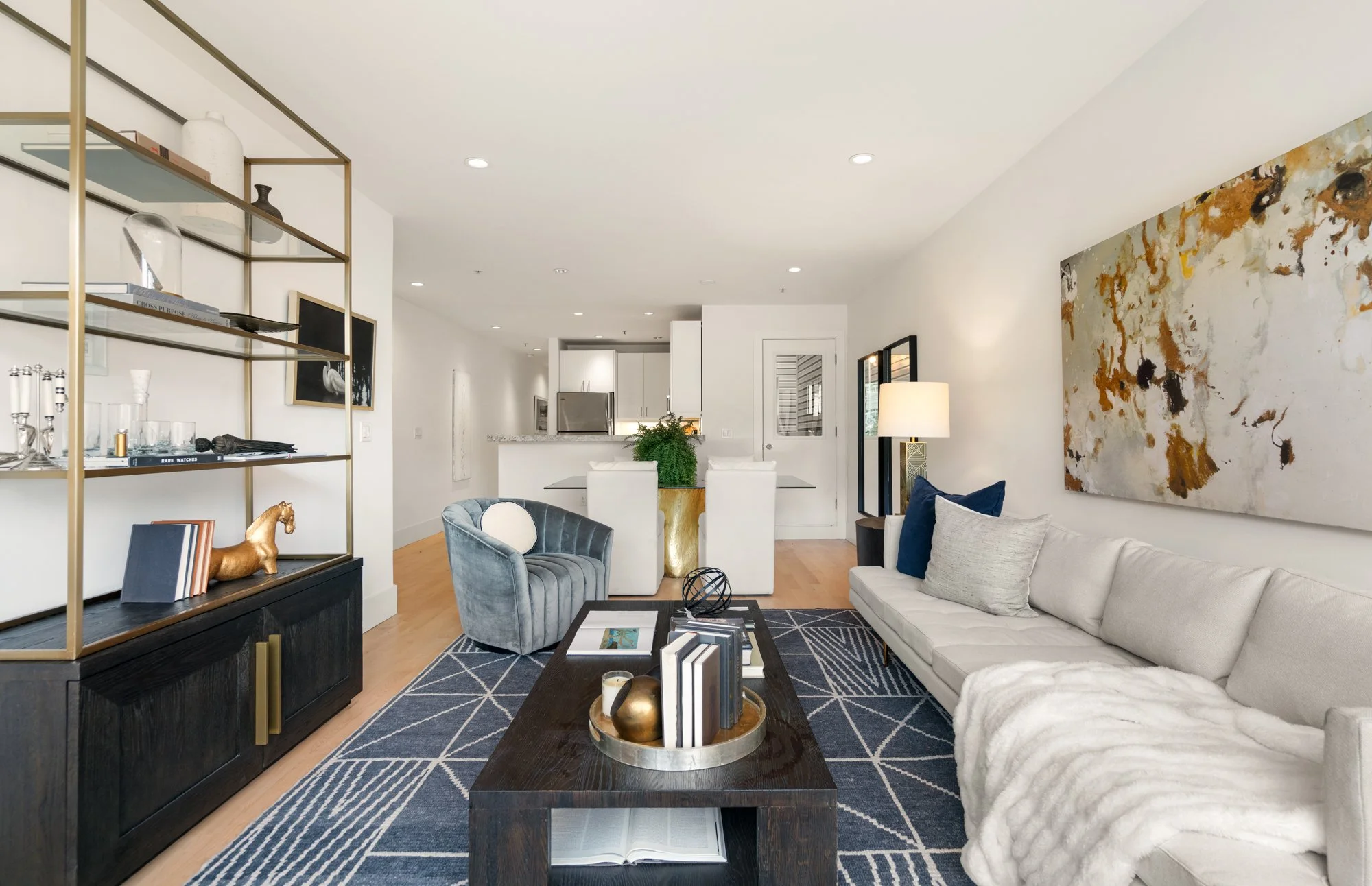 Modern living room with a white sofa, gray armchair, black coffee table, and a colorful abstract painting on the wall.