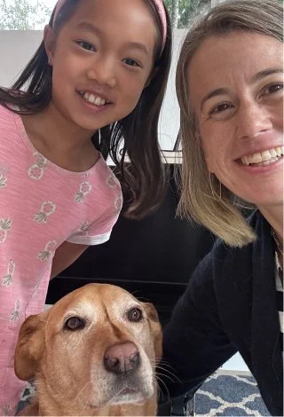 A young girl, a woman, and a dog taking a selfie together.