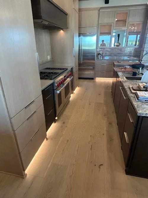 Modern kitchen with wood cabinets, stainless steel appliances, and under-cabinet lighting.