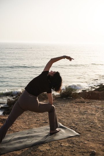 Frau macht Yoga-Übung am Strand bei Sonnenuntergang.
