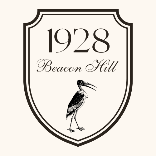 A logo with a shield shape that reads '1928 Beacon Hill' and features a black and white heron standing at the bottom.