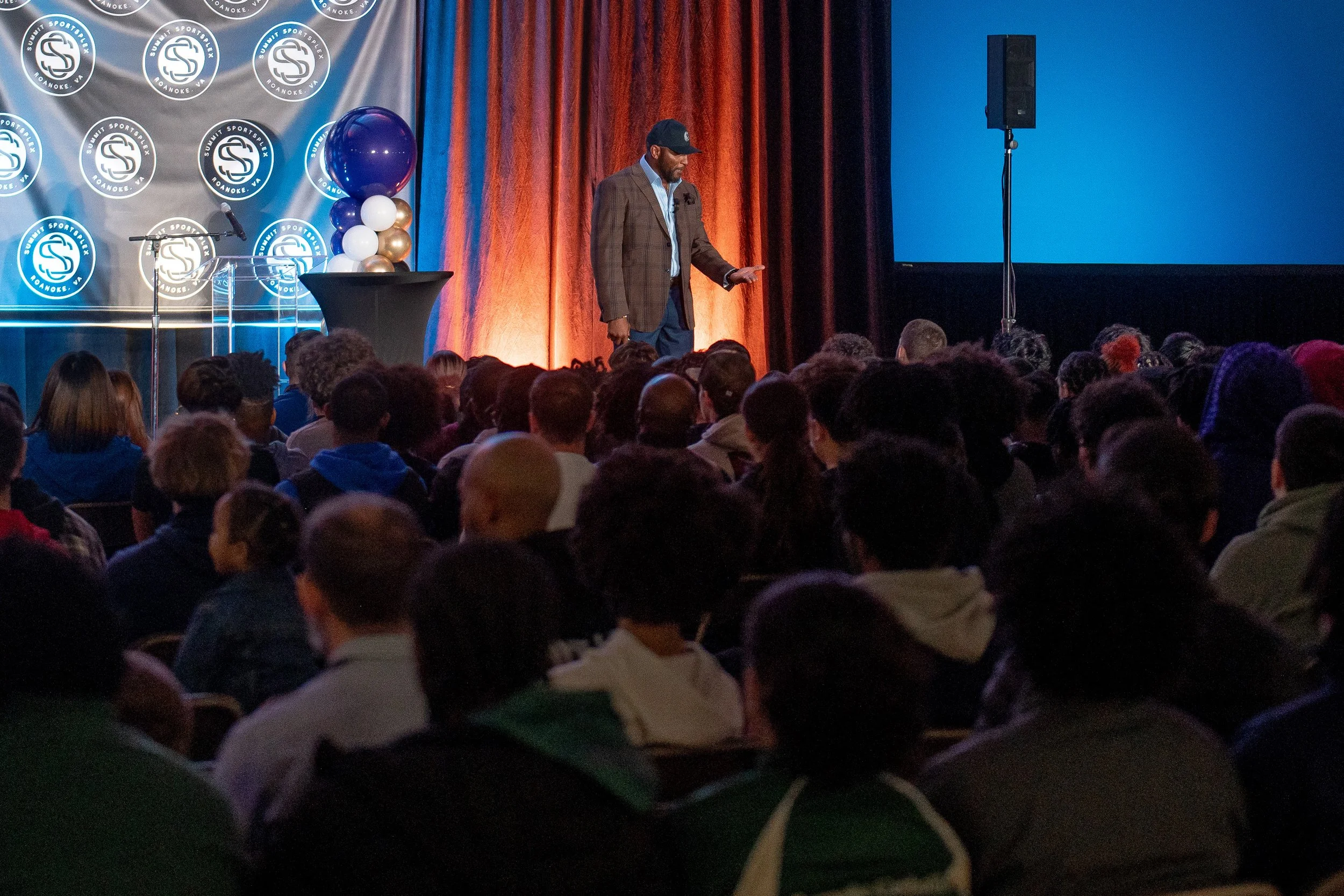 Ray Lewis speaks on stage at Summit Sportsplex in Roanoke, VA during a community event for local students, athletes, and partners.