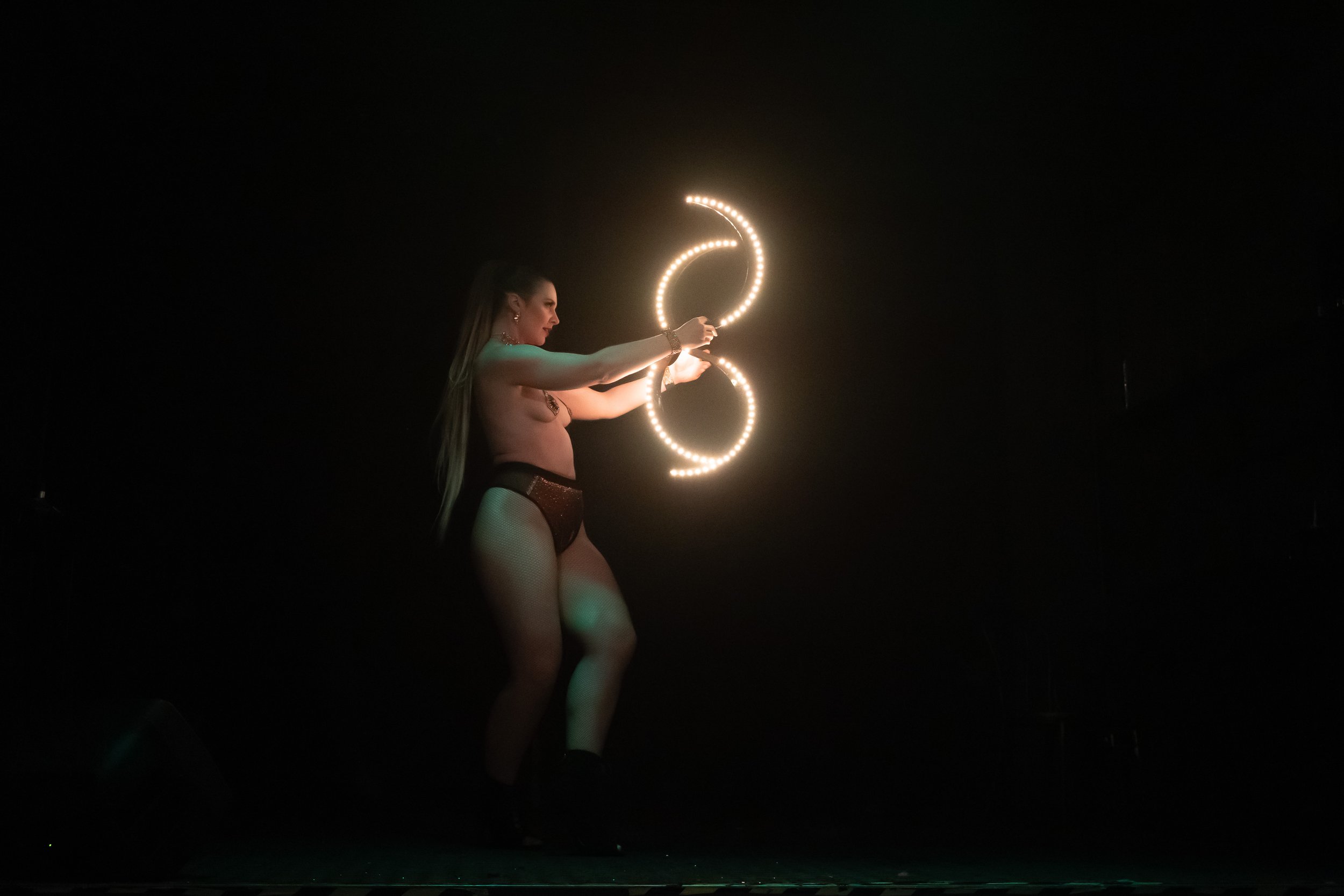 A woman performing a dance with illuminated hoops in a dark setting.