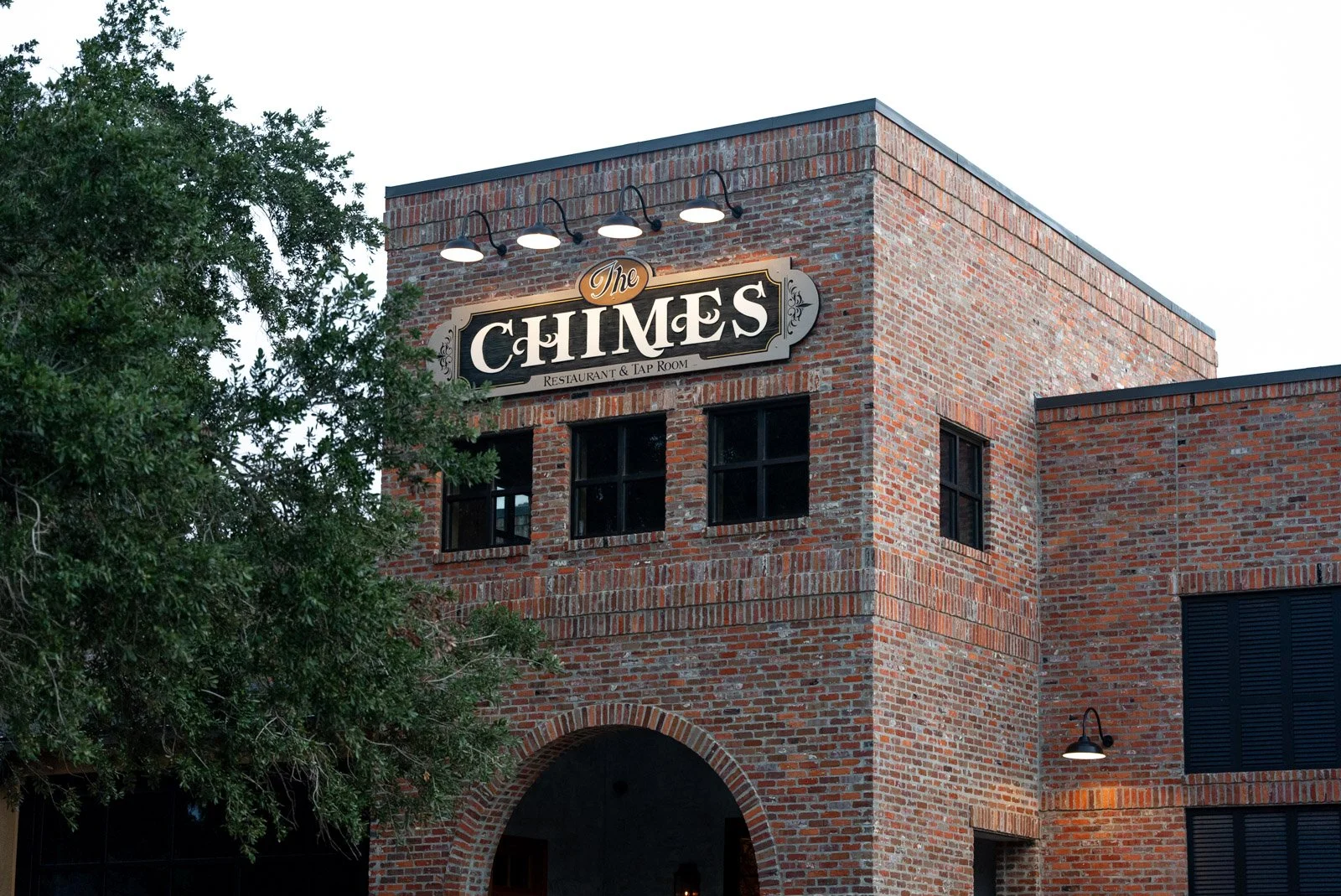 Exterior of a brick building with a sign stating 'The Chimes Restaurant & Tap Room' and some exterior lights.