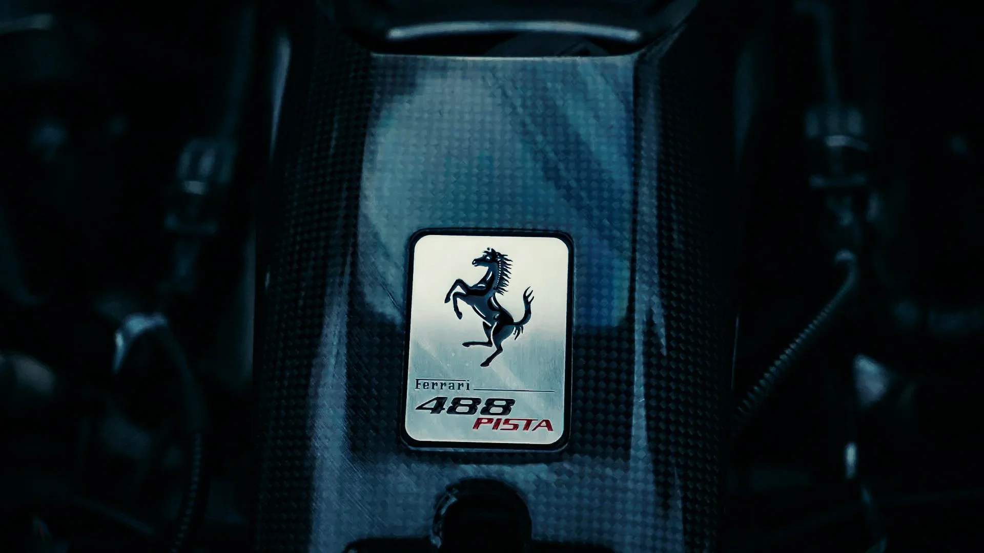 Close-up of a Ferrari 488 Pista engine cover with the Ferrari logo and model name.