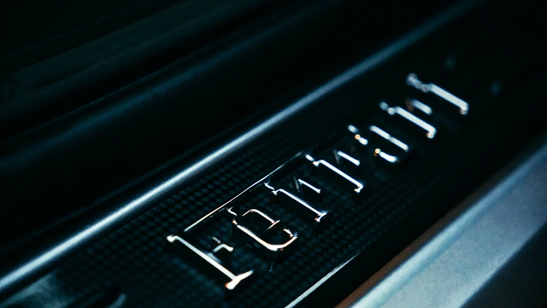 Close-up of the Ferrari logo on a dark, textured surface with metallic accents.
