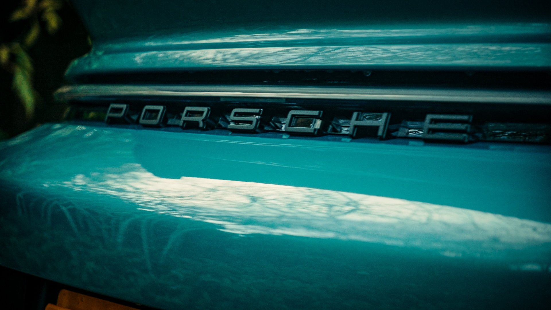 Close-up of a blue vintage Porsche car front with the Porsche emblem.