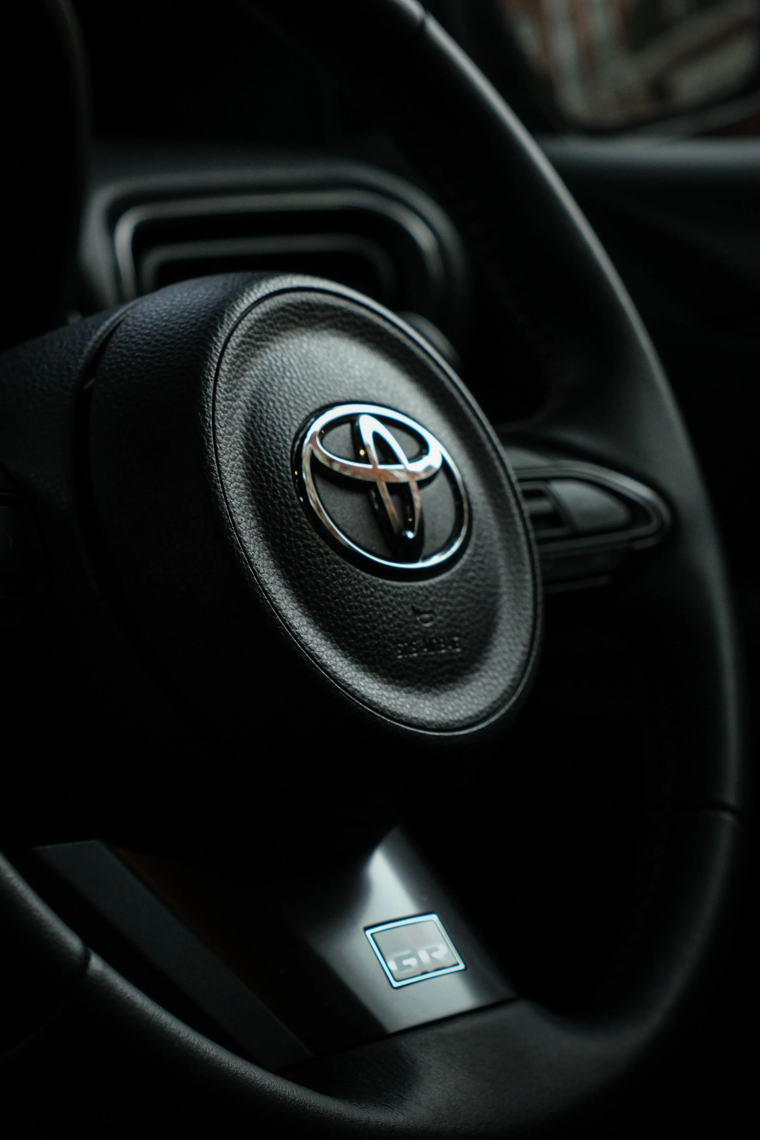 Close-up of a Toyota steering wheel in a car interior.