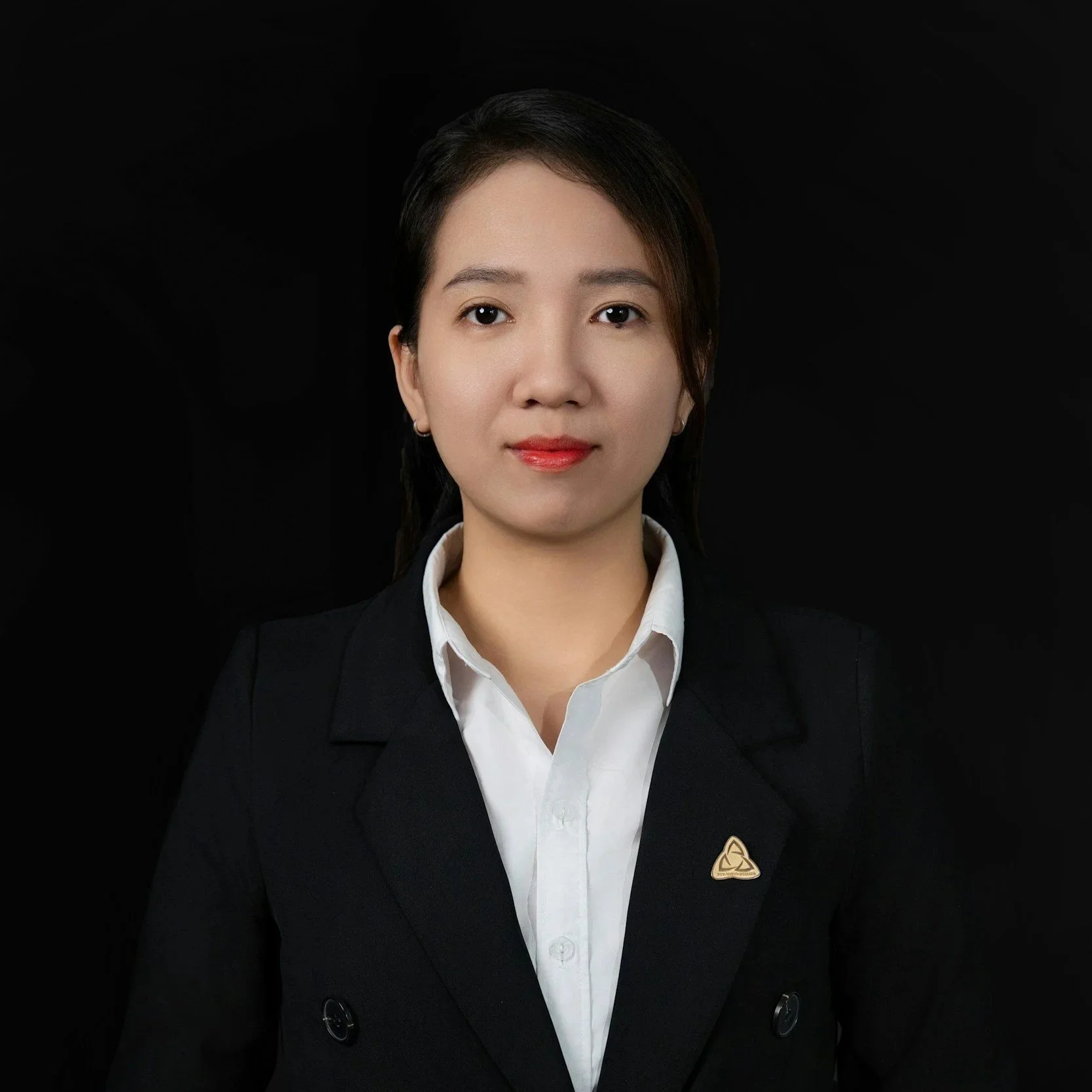 A young woman with red hair tied in a bun, wearing glasses, a white t-shirt, and denim overalls, smiling at the camera.