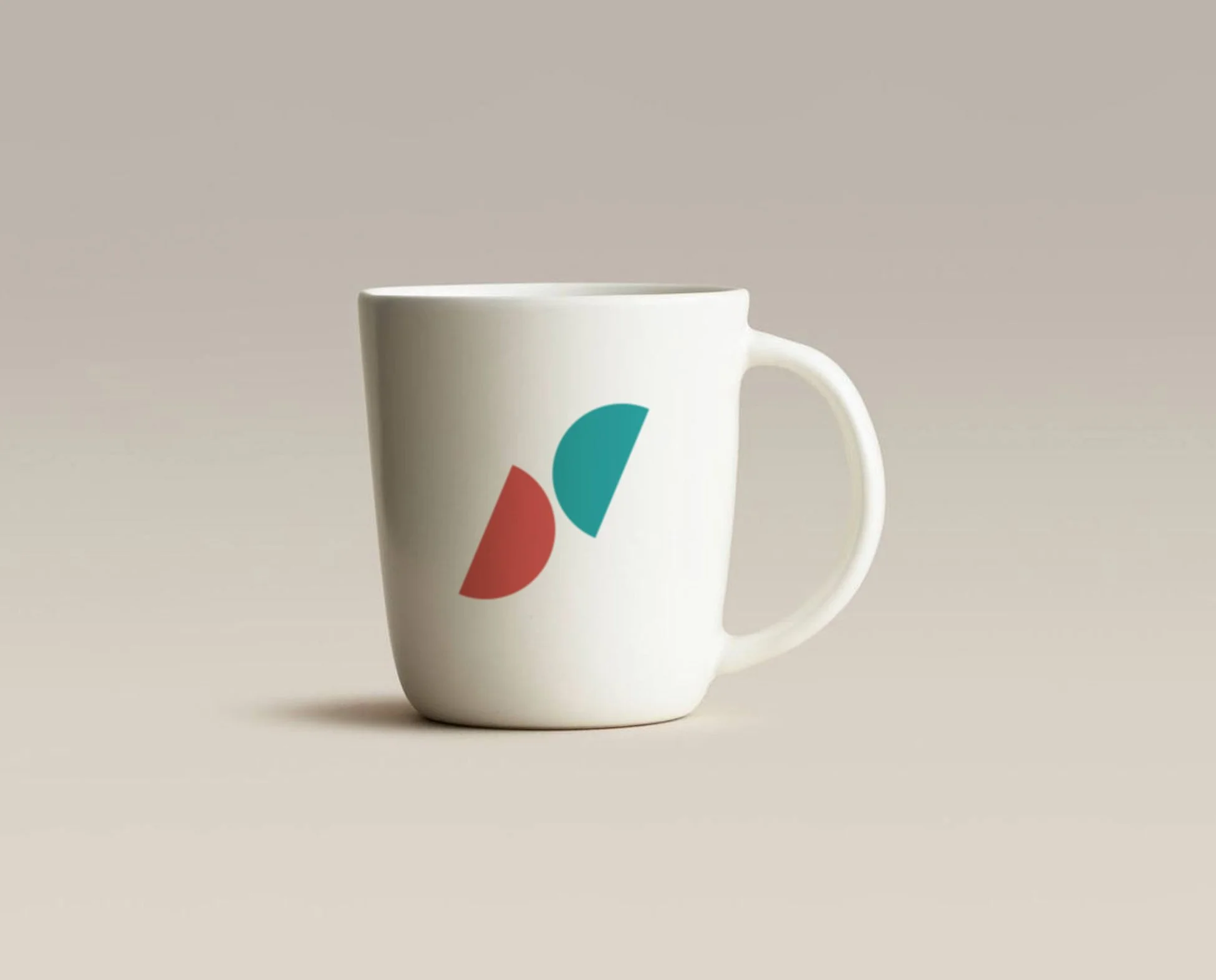 Taza blanca con un diseño de formas geométricas en colores rojo y azul sobre fondo beige_serveis socials_vilasar de mar_diseño identidad de estudio berlin