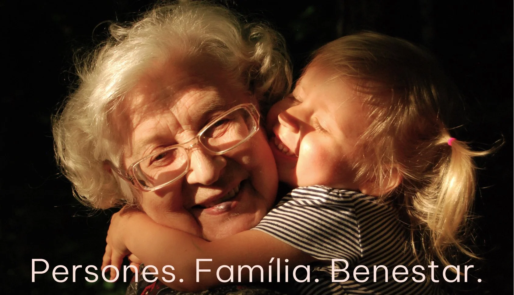 Una abuela y una niña se abrazan y se sonríen durante la noche, destacando los lazos familiares y la felicidad compartida_Llar carme_premia de mar_diseño identidad de estudio berlin