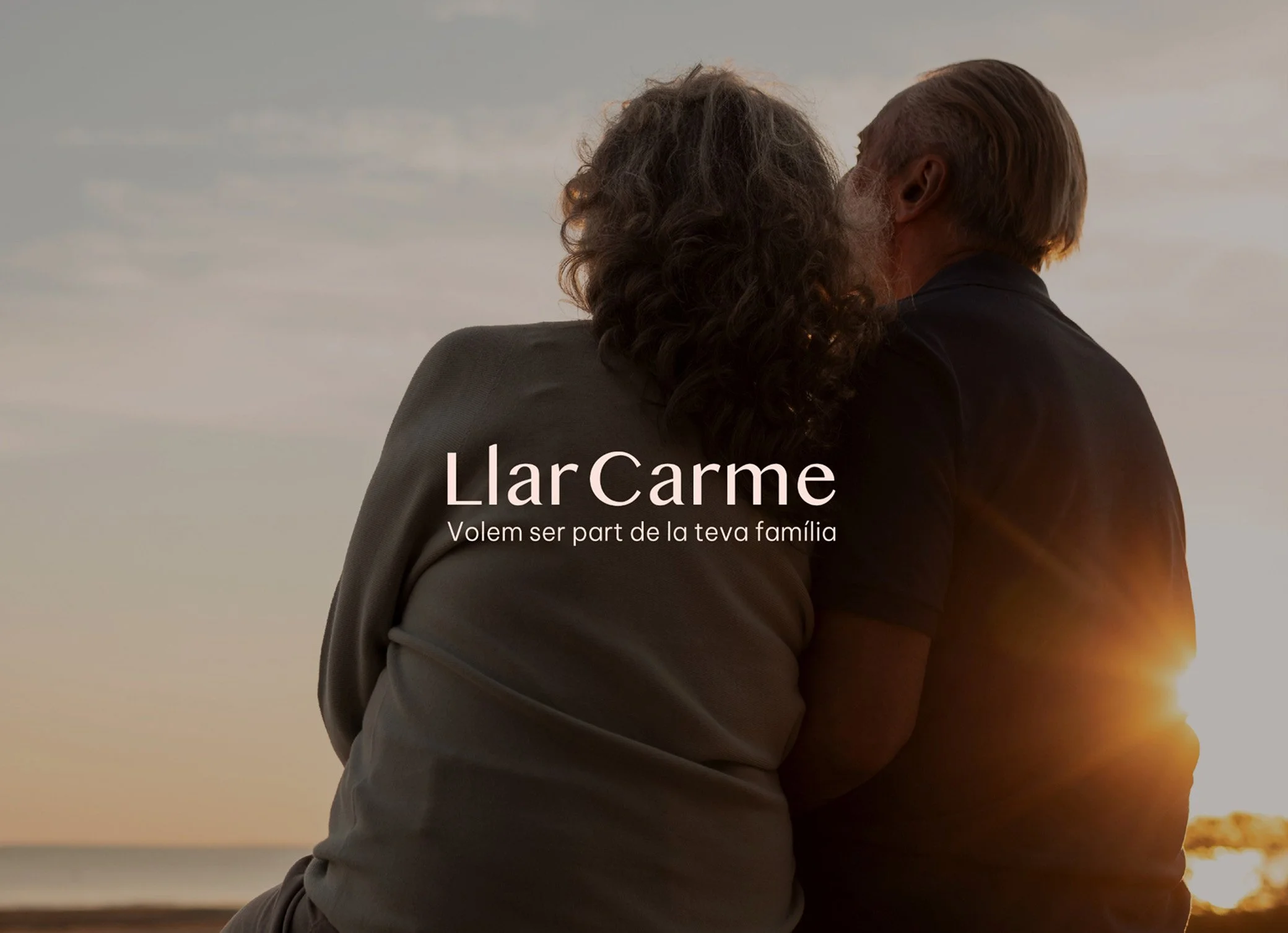 Una pareja envejecida abrazada y mirándose en un atardecer en la playa con logo de llar carme_Llar carme_premia de mar_diseño identidad de estudio berlin