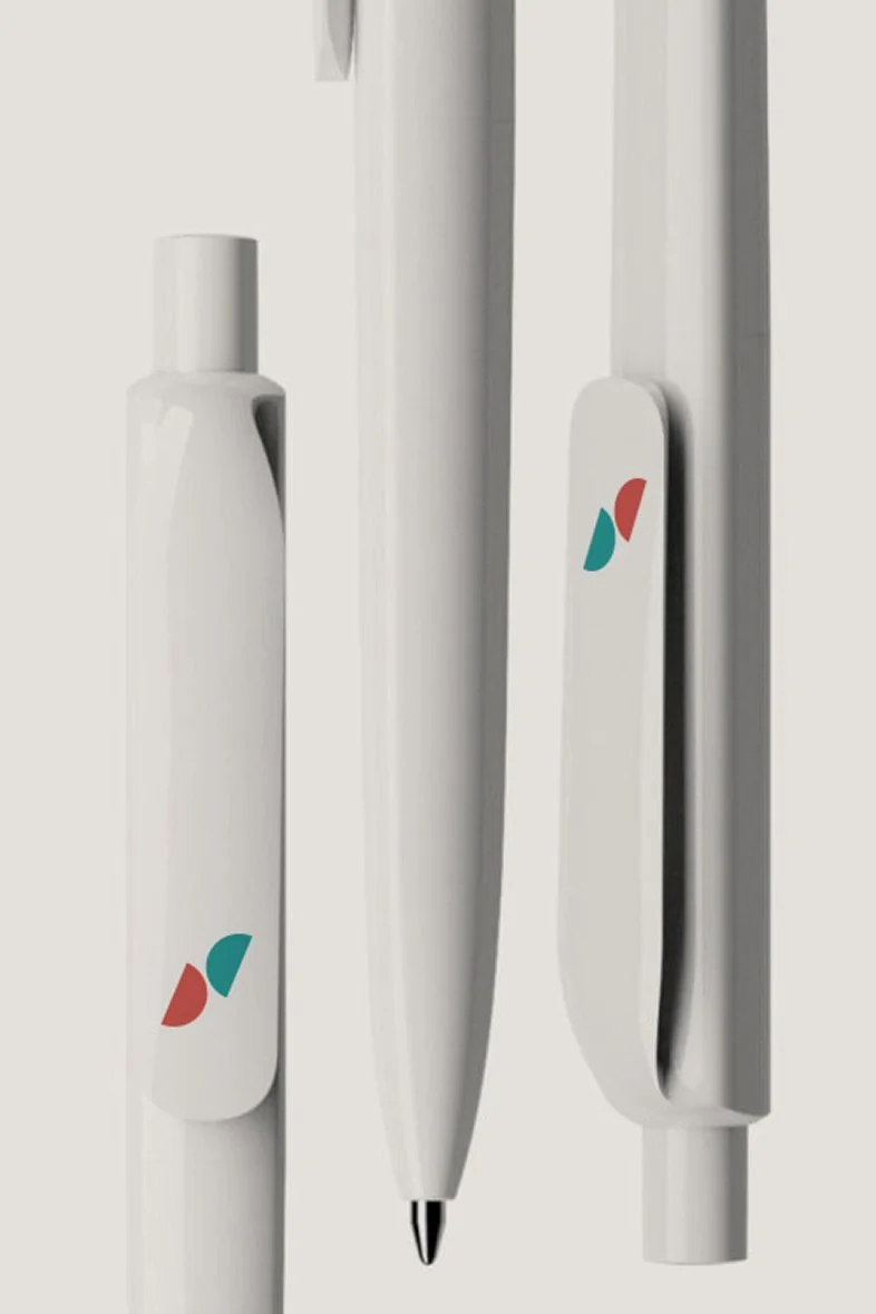 Conjunto de útiles de oficina blancos, incluyendo bolígrafo y otros objetos, con detalles en colores rojo y verde_serveis socials_vilasar de mar_diseño identidad de estudio berlin