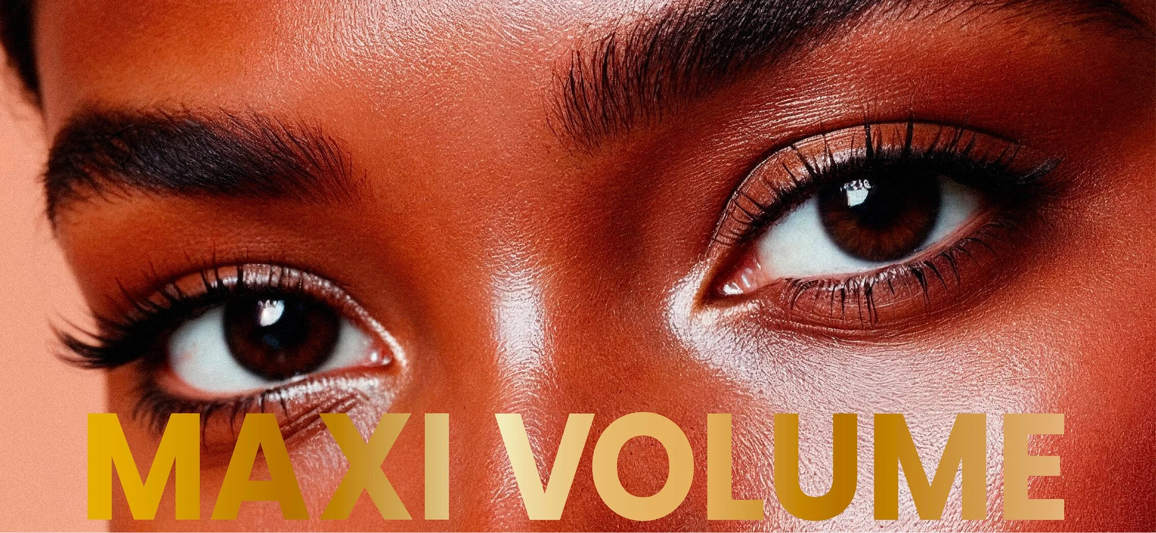 Primer plano de los ojos de una persona con maquillaje y cejas bien arregladas, fondo de tono cálido. Texto en la parte inferior que dice 'MAXI VOLUME' en letras grandes y doradas_Mascaras deliplus_mercadona_Packaging de cosmetica de estudio berlin