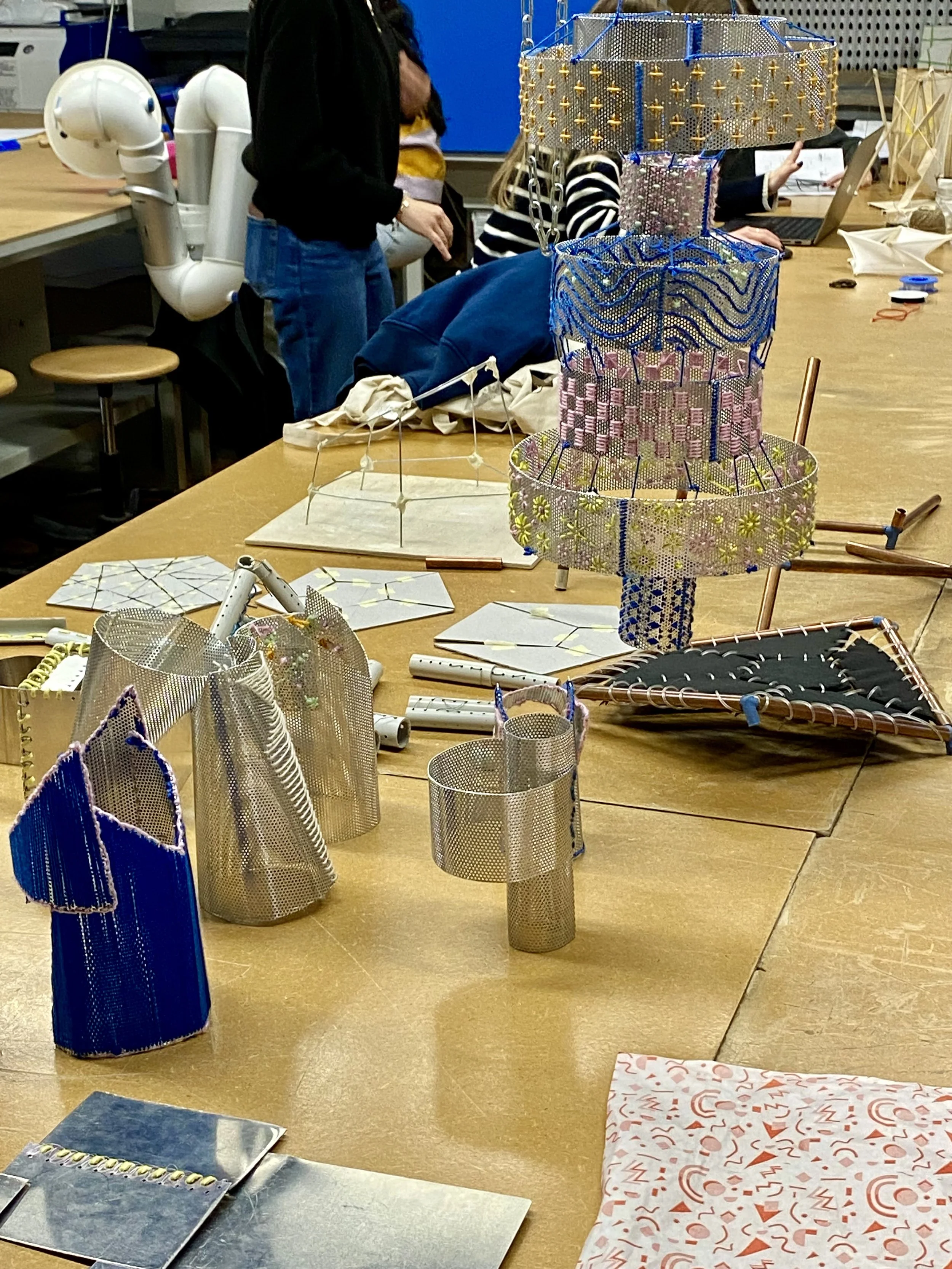 Prototipi di lampade o strutture artistiche realizzate con materiali metallici e tessuti colorati.