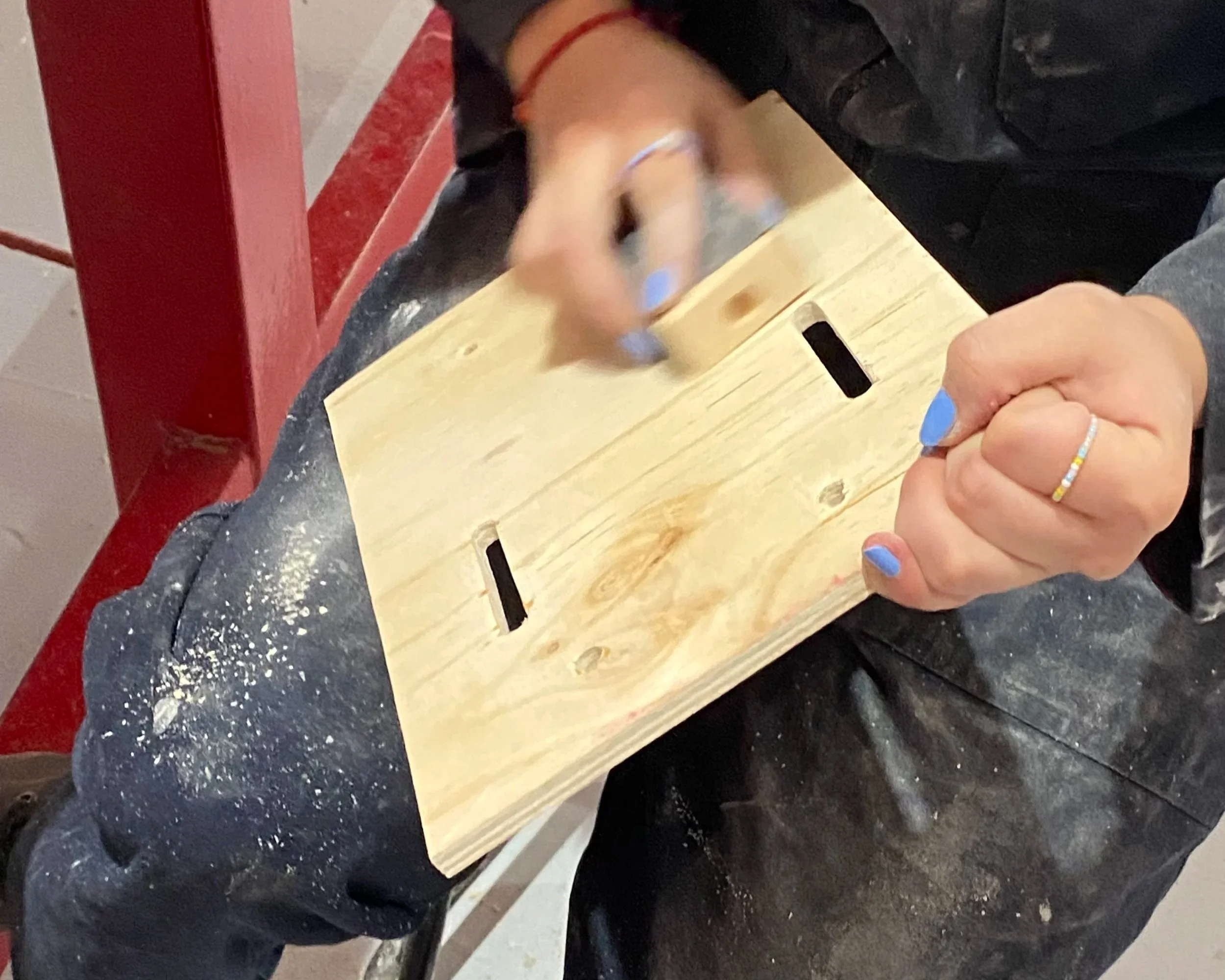 Persona che lavora con un pezzo di legno, usando un martello, con smagliature di colla o residui di legno.