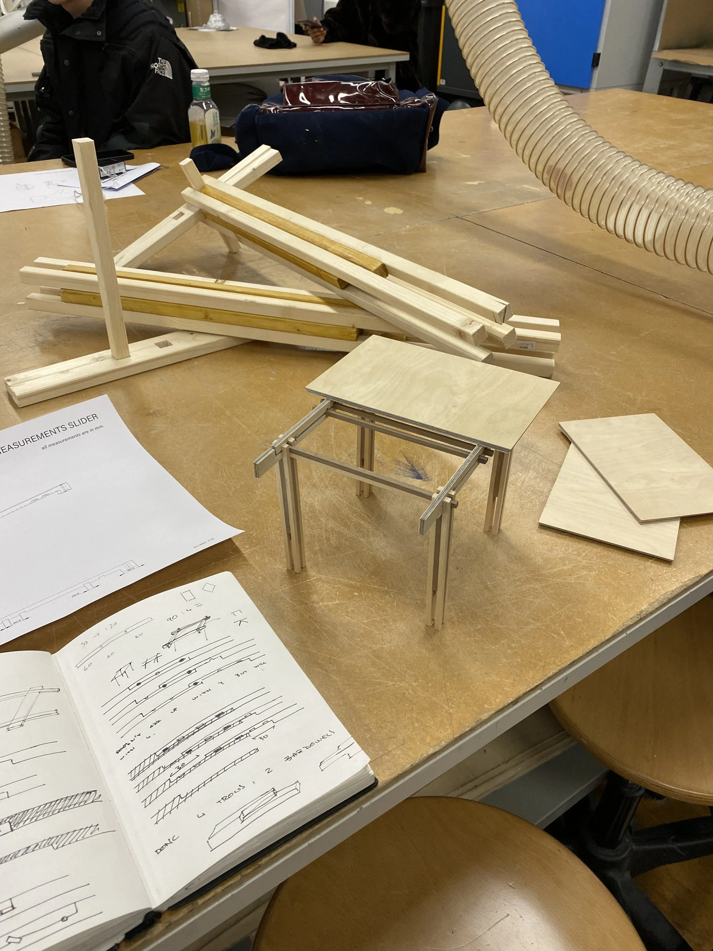 Modello di una struttura in legno con tavola sopra e istruzioni di montaggio.