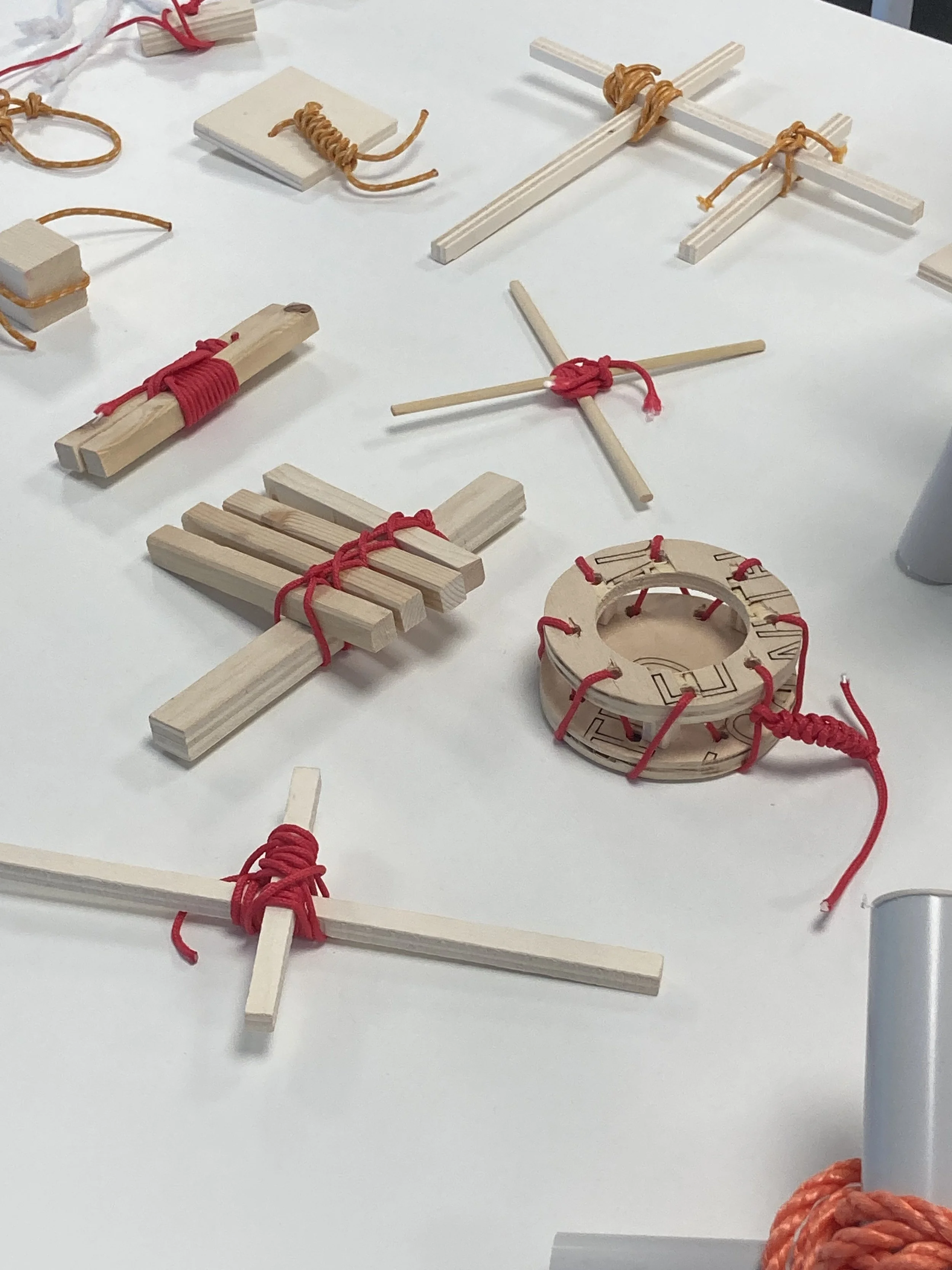 Varie figure di legno e bambù legate con nastri di corda, disposte sul tavolo.