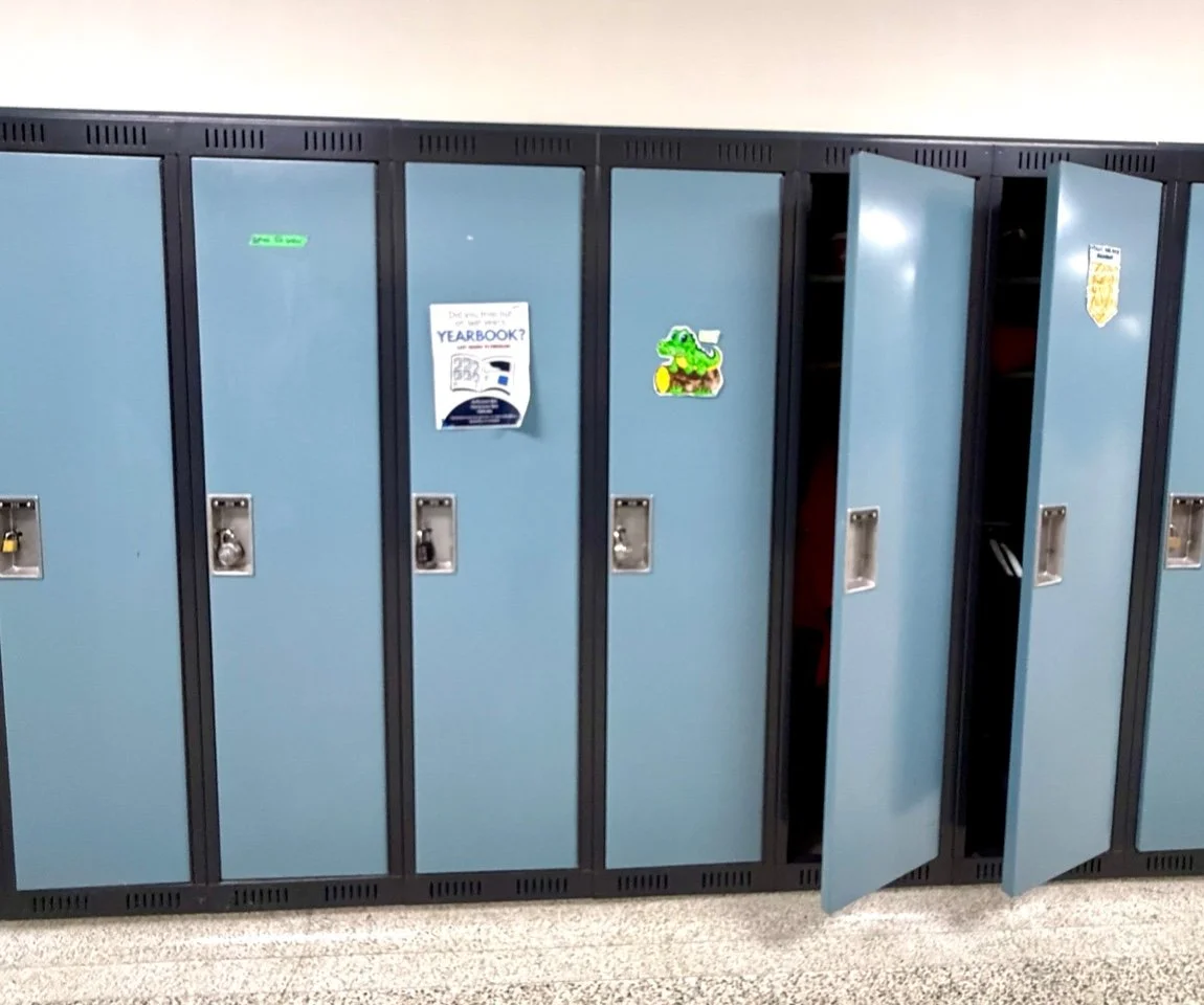 School lockers, some open and some closed, with stickers and papers on the doors.