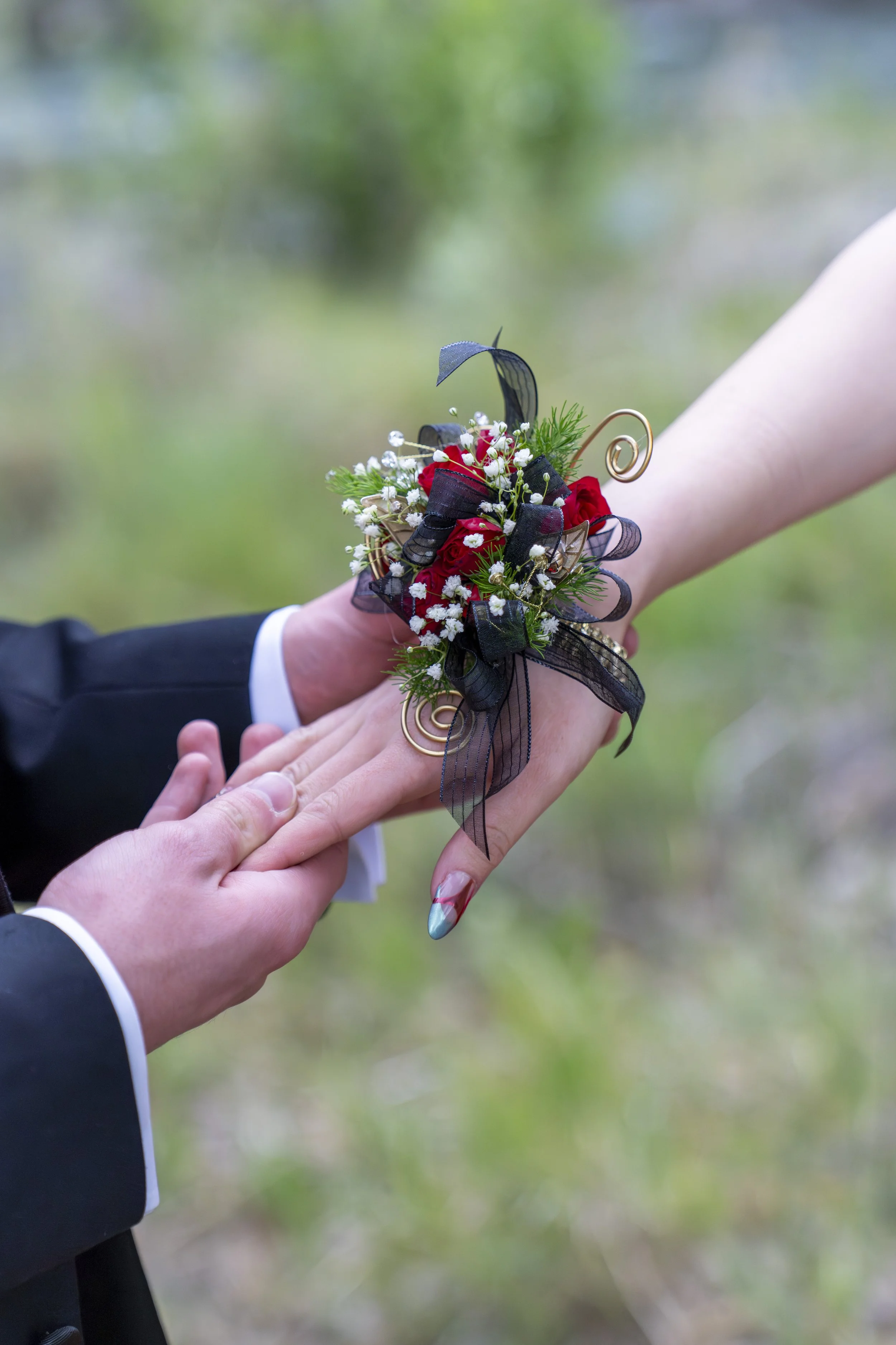 A man places a corsage on the wrist of his prom date.