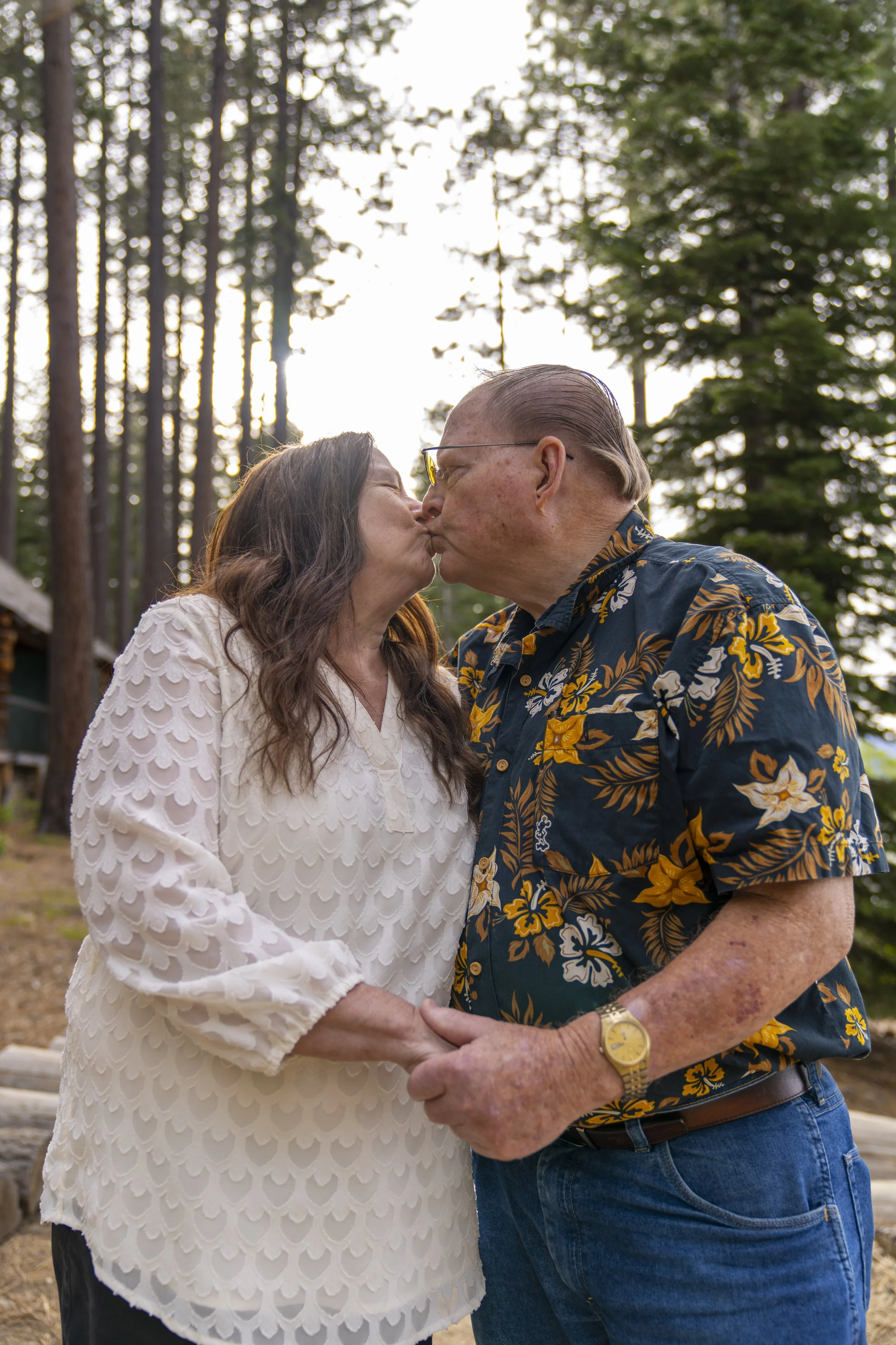 An elderly couple share a kiss during a photoshoot in an alpine wilderness.