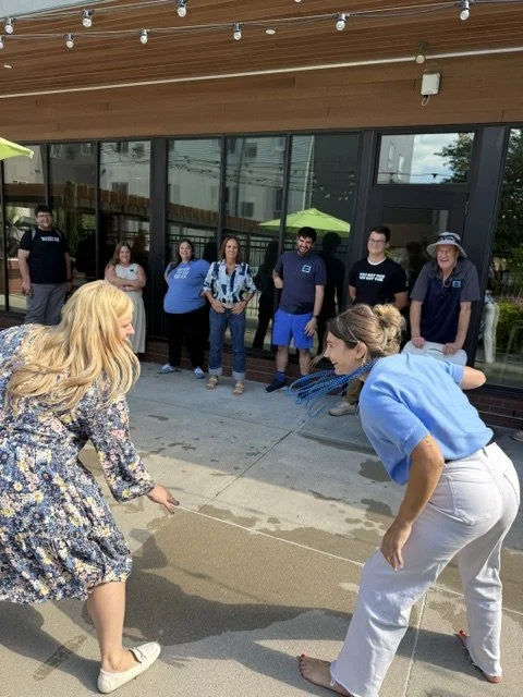 Two women playing a game on the sidewalk with spectators watching.
