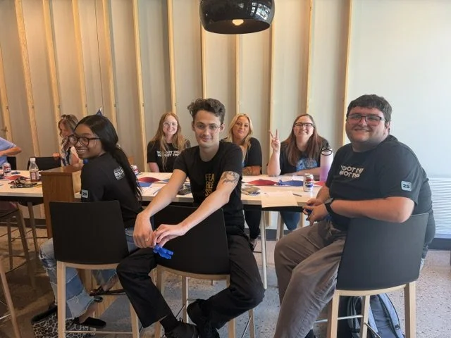 Group of people sitting at tables in a conference room, smiling and posing for the photo.