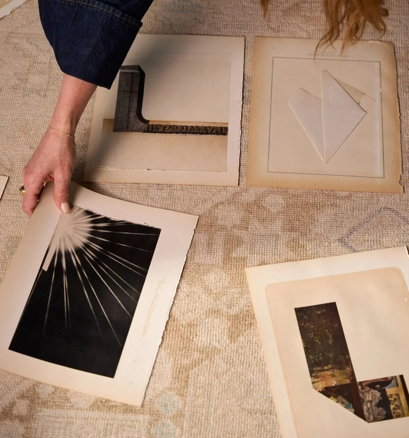 Photos of various artwork and framed pictures laid out on a beige textured surface.