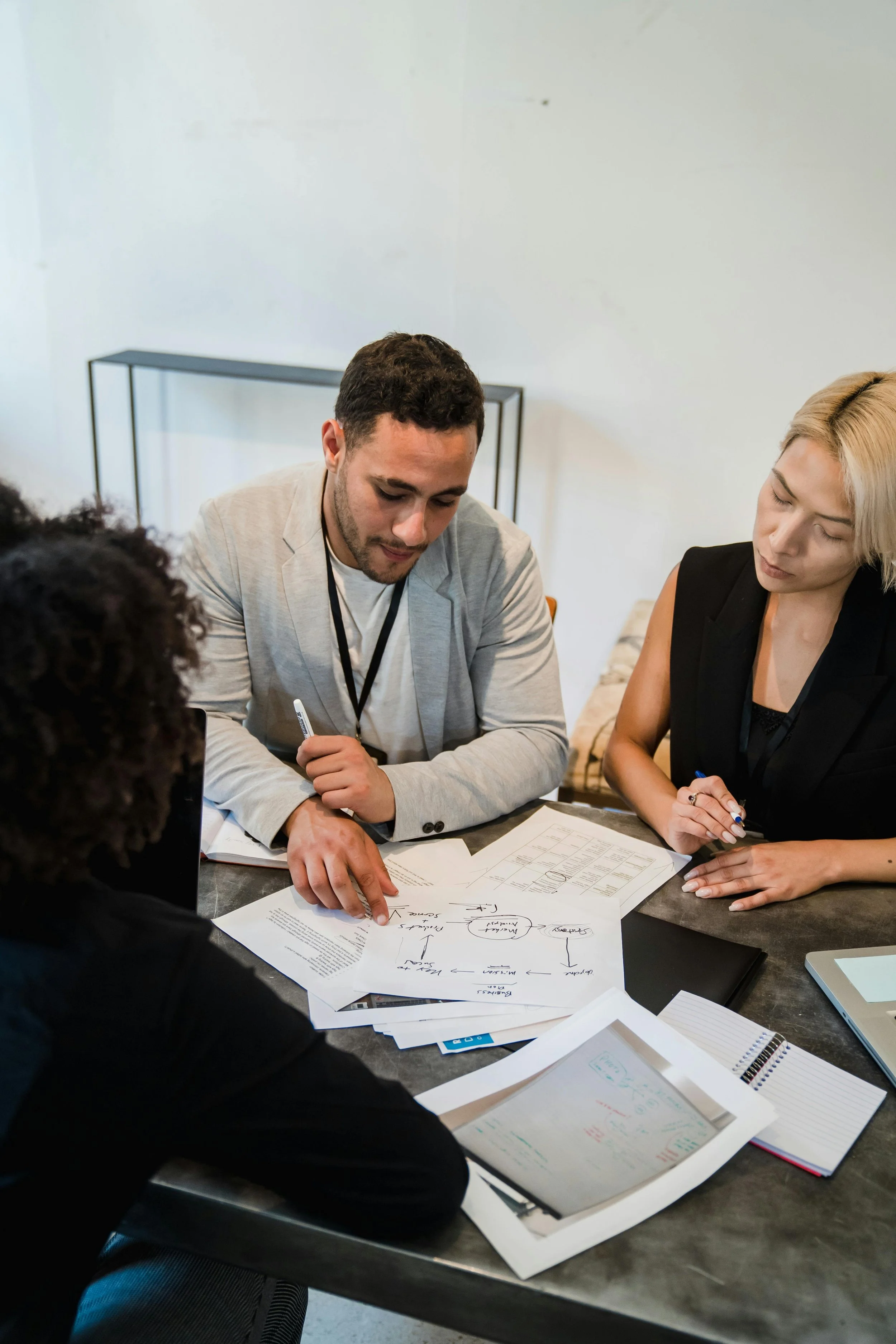 Four people in a business meeting reviewing documents and notes on a table.