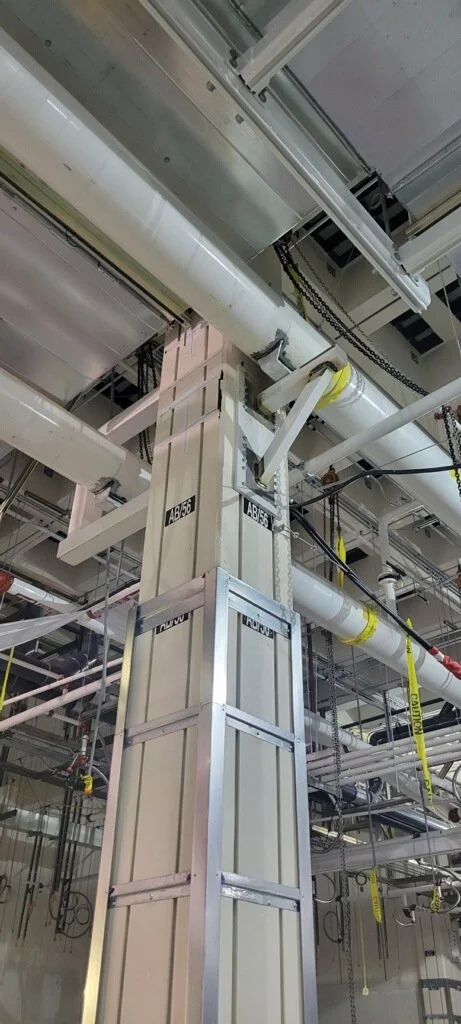 Construction site with pipes, ducts, and a scaffold inside a building.